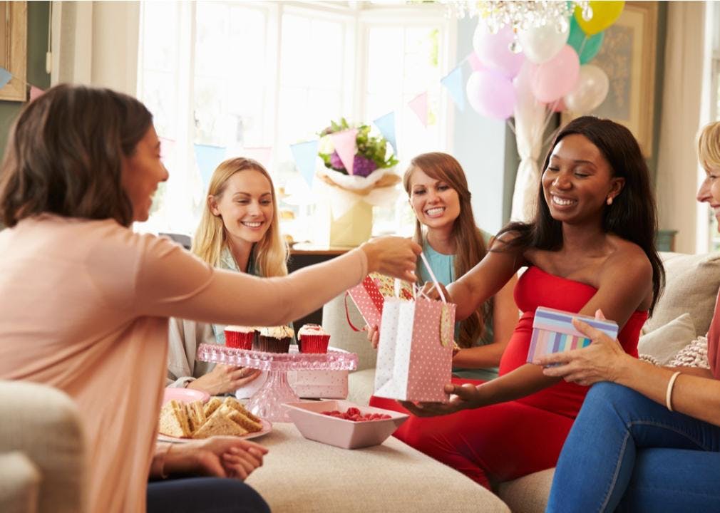 Gift exchange at a baby shower with five women sitting in a living room