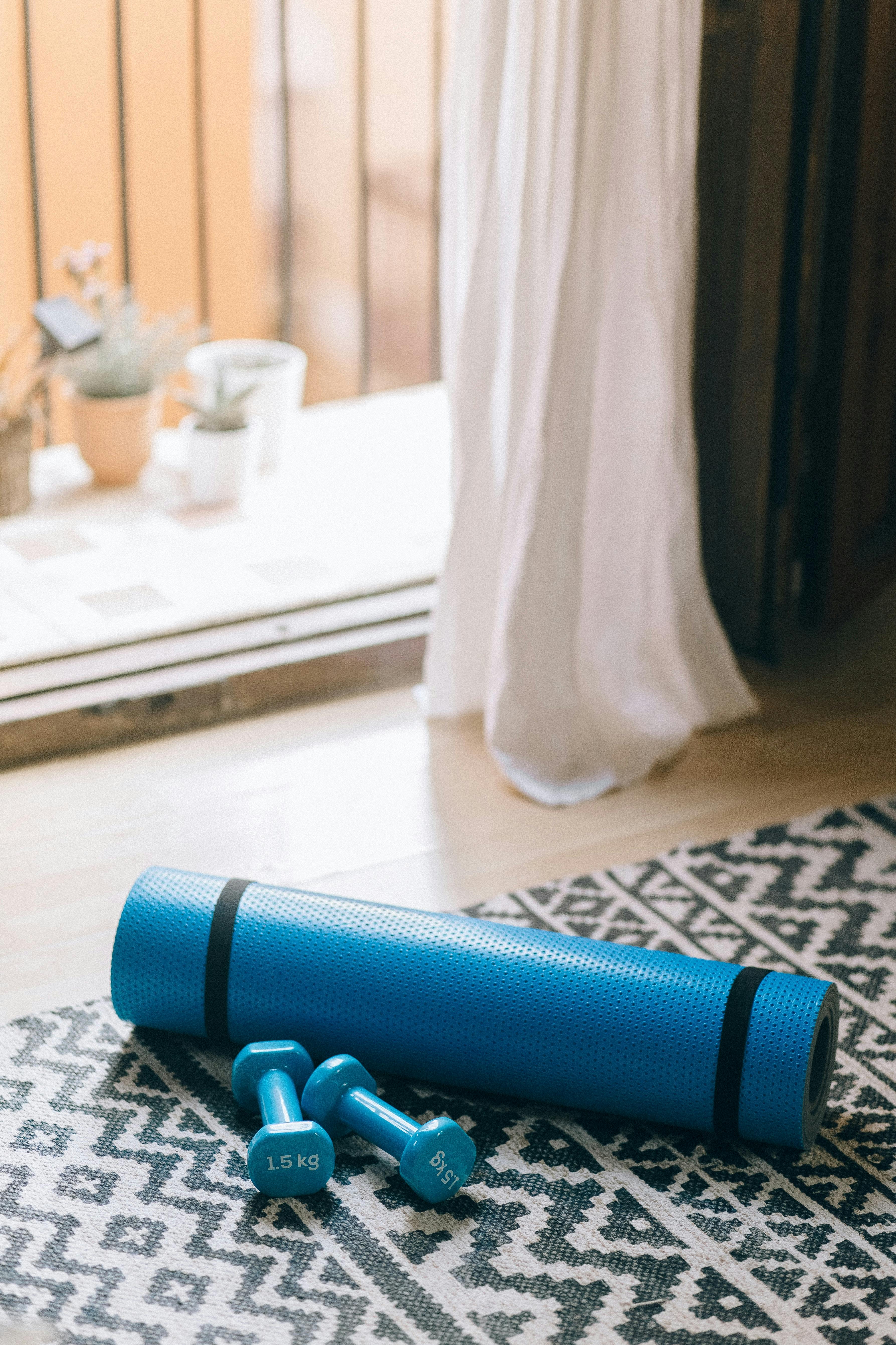Two hand weights and a yoga mat laying on the ground indoors
