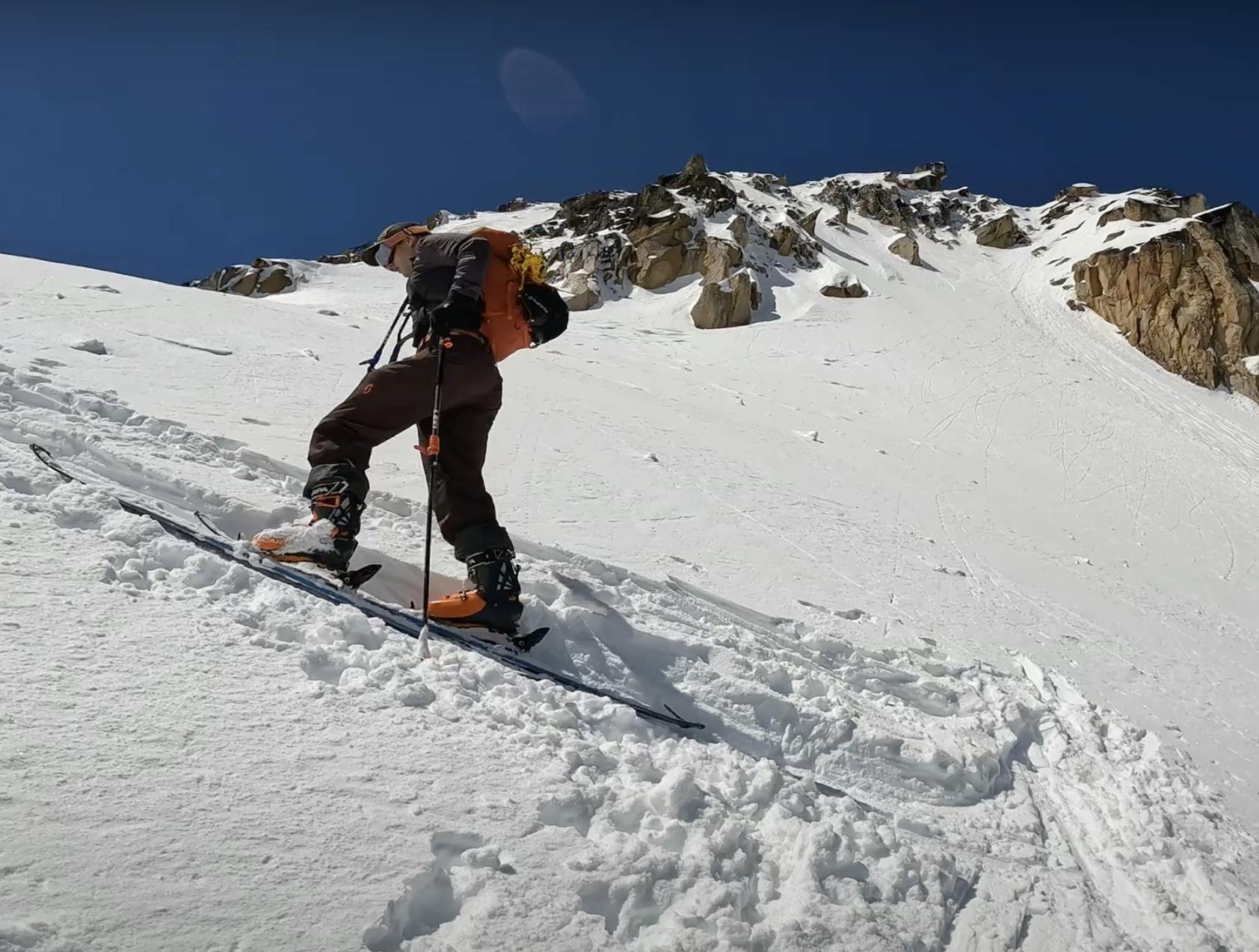 A skier skinning up a steep hill.