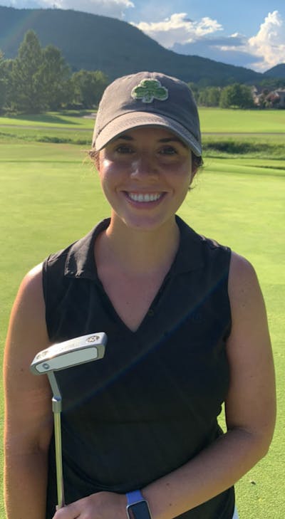 A woman on a golf course holding the Odyssey Women's White Hot OG #1 Wide S Putter.