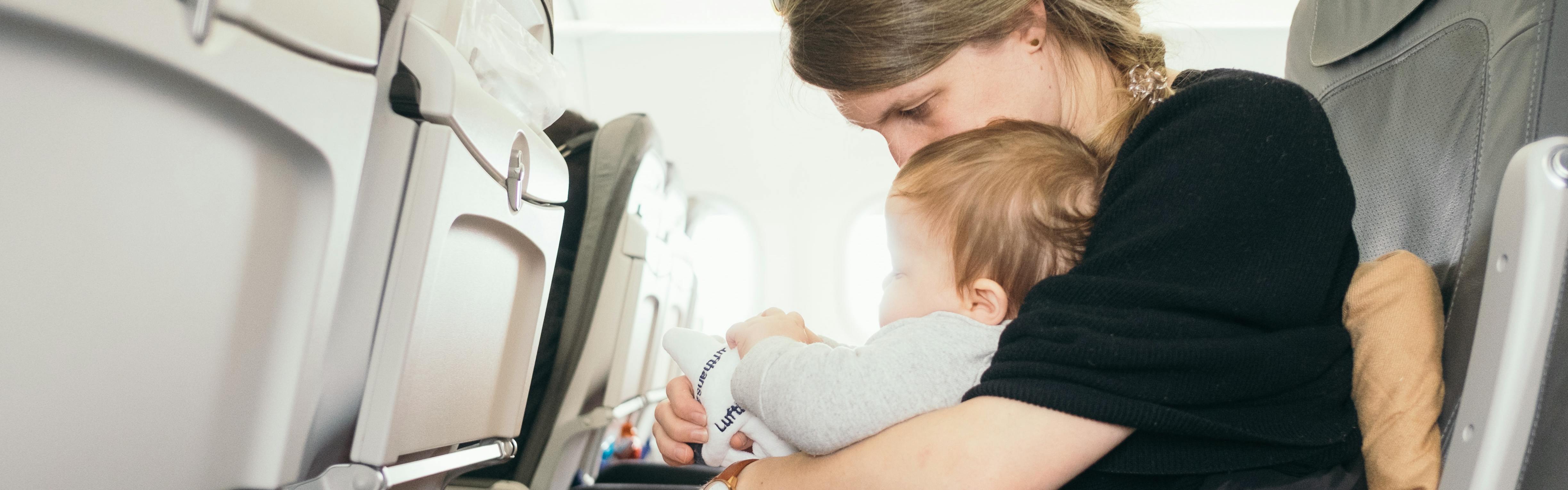A baby and a mom sitting in seats on an airplane.