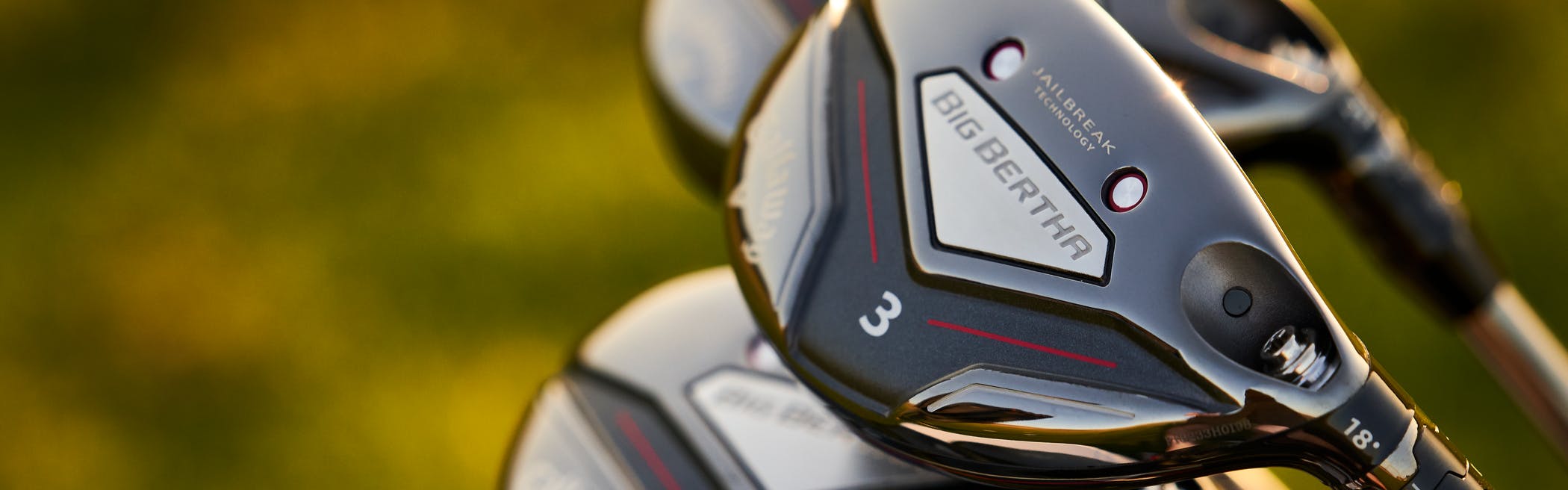 A cluster of Callaway Big Bertha irons in front of an out-of-focus green background. 