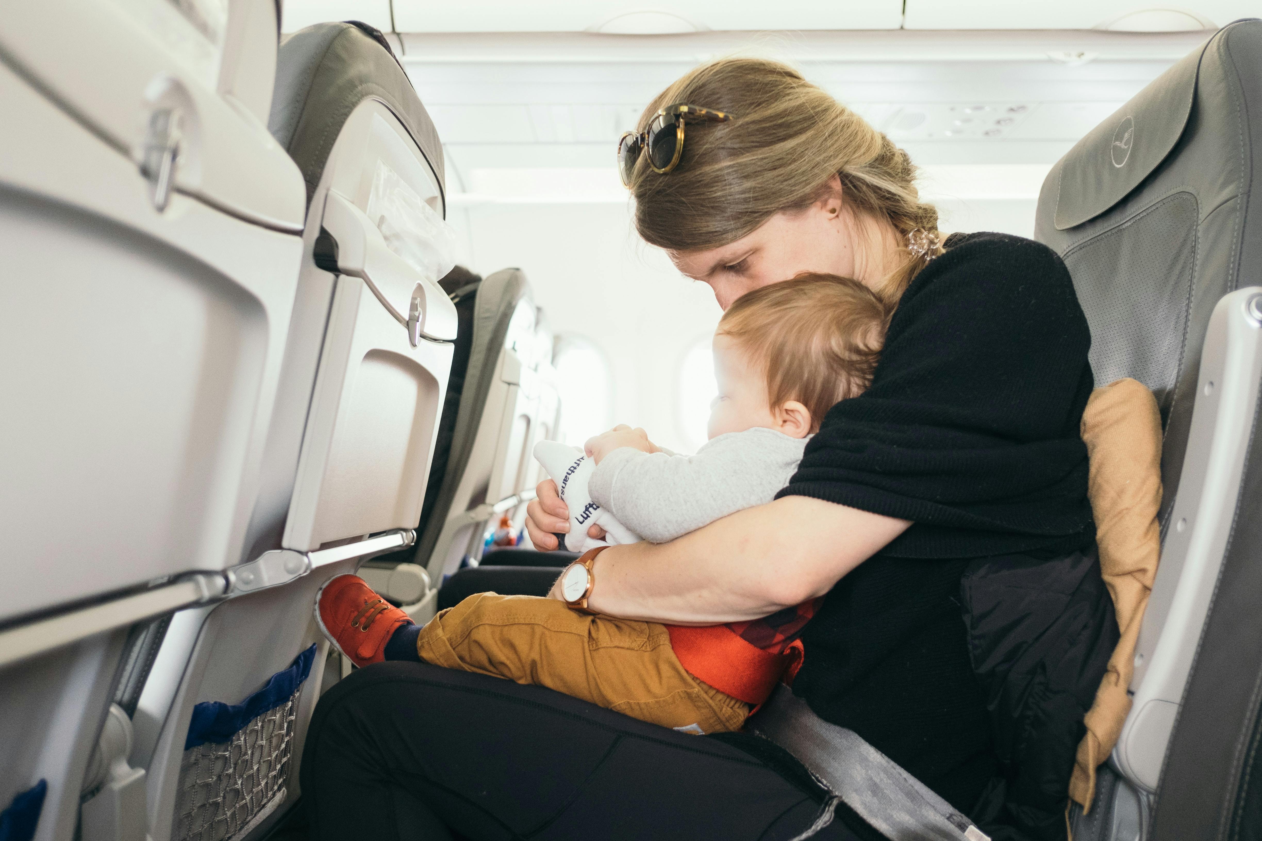 A baby and a mom sitting in seats on an airplane.