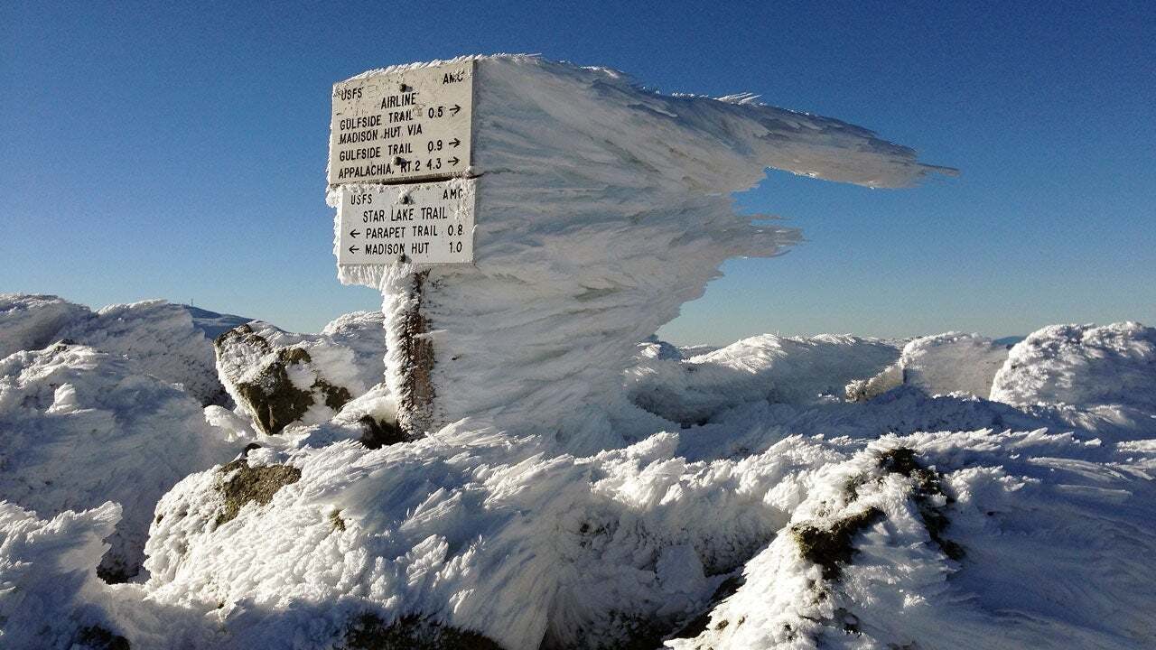 A sign with a bunch of snow and ice on it. 