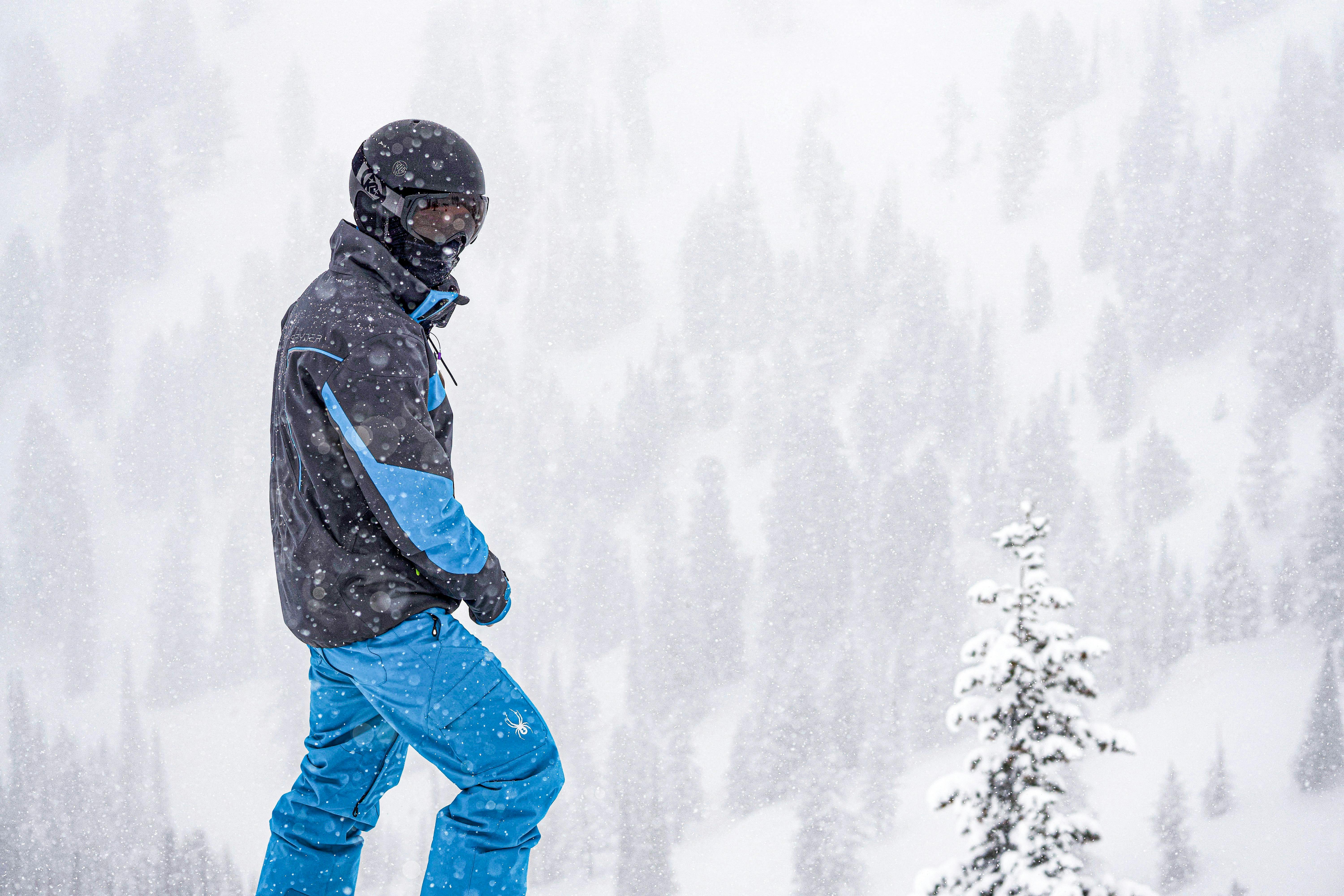 A skier with blue pants standing at the top of a snowy mountain. 