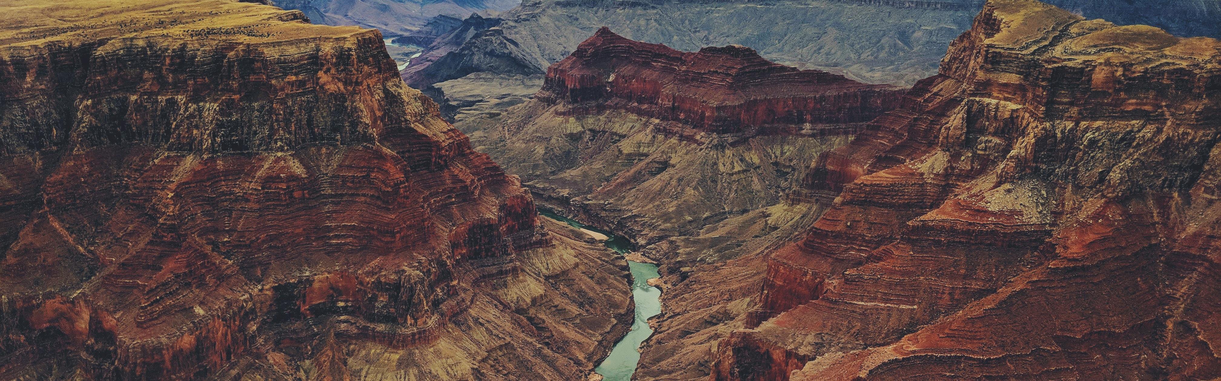 An aerial view of a river snaking through red and yellow canyons