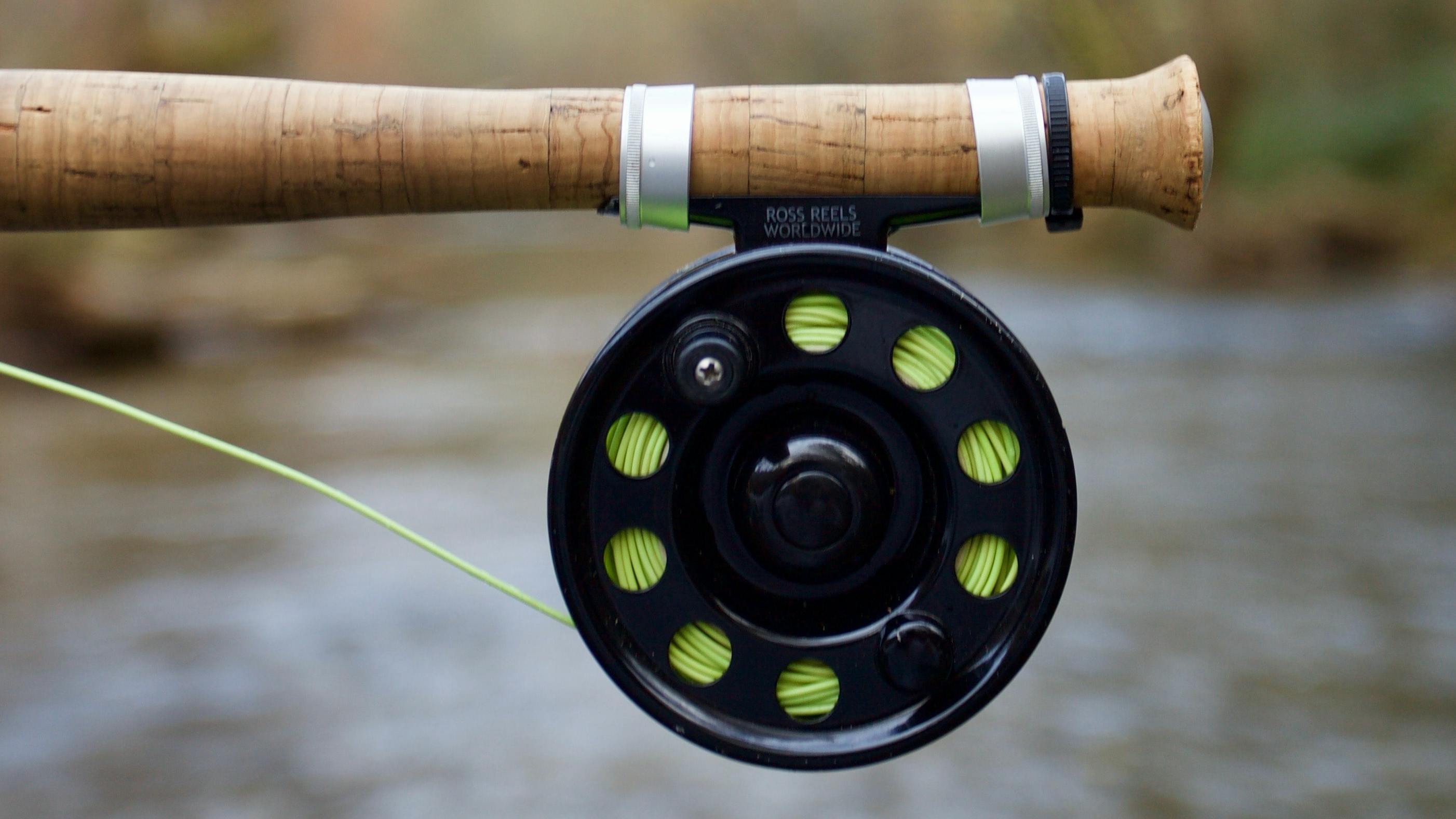 The handle of a fly rod with a reel attached to it. 