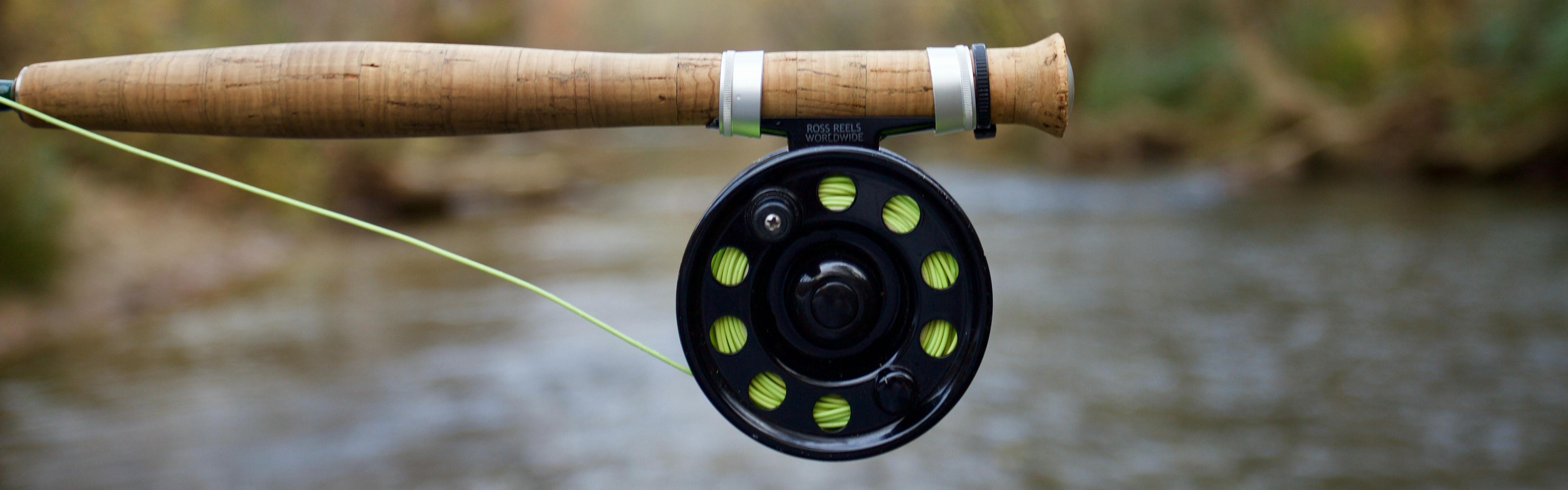 The handle of a fly rod with a reel attached to it. 