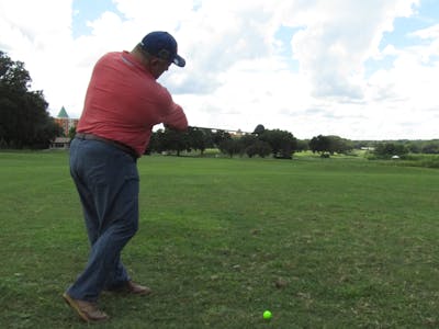 A man on a golf course taking a swing with the Tour Edge Exotics E722 Fairway Wood.