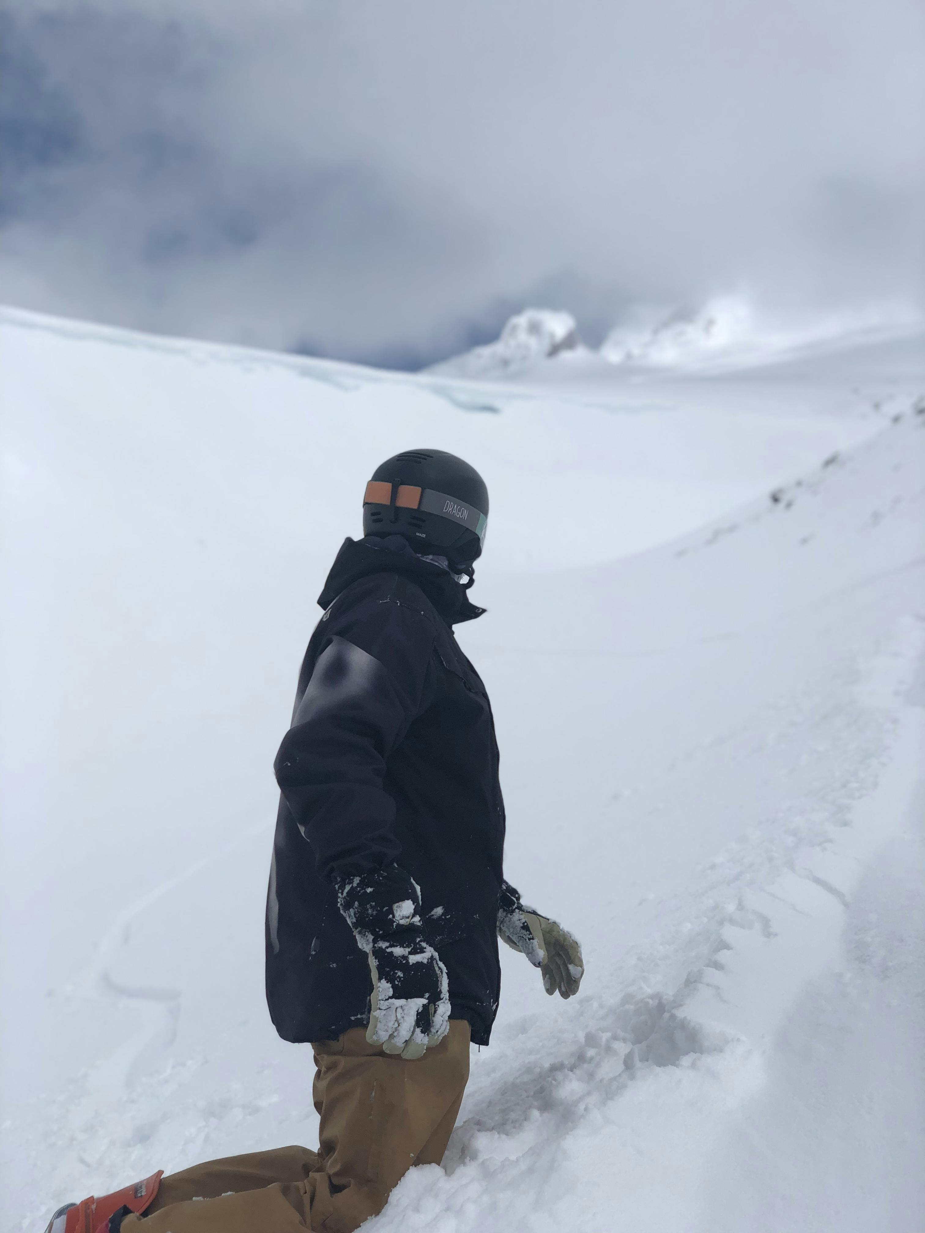 A snowboarder looking up at a snowy mountain. 