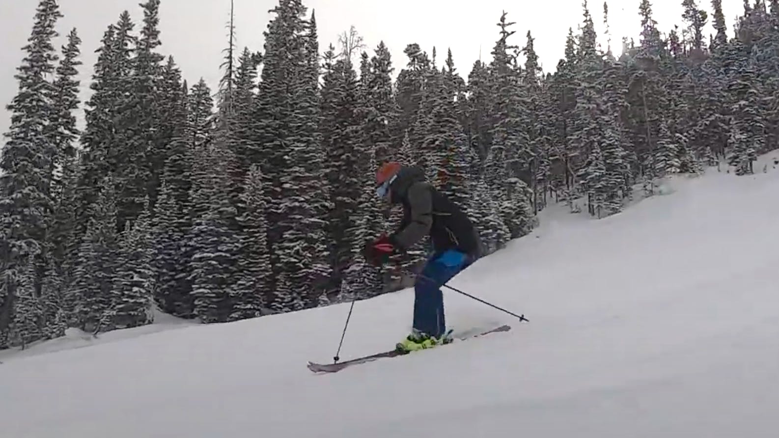 A man in blue pants skis down a mountain