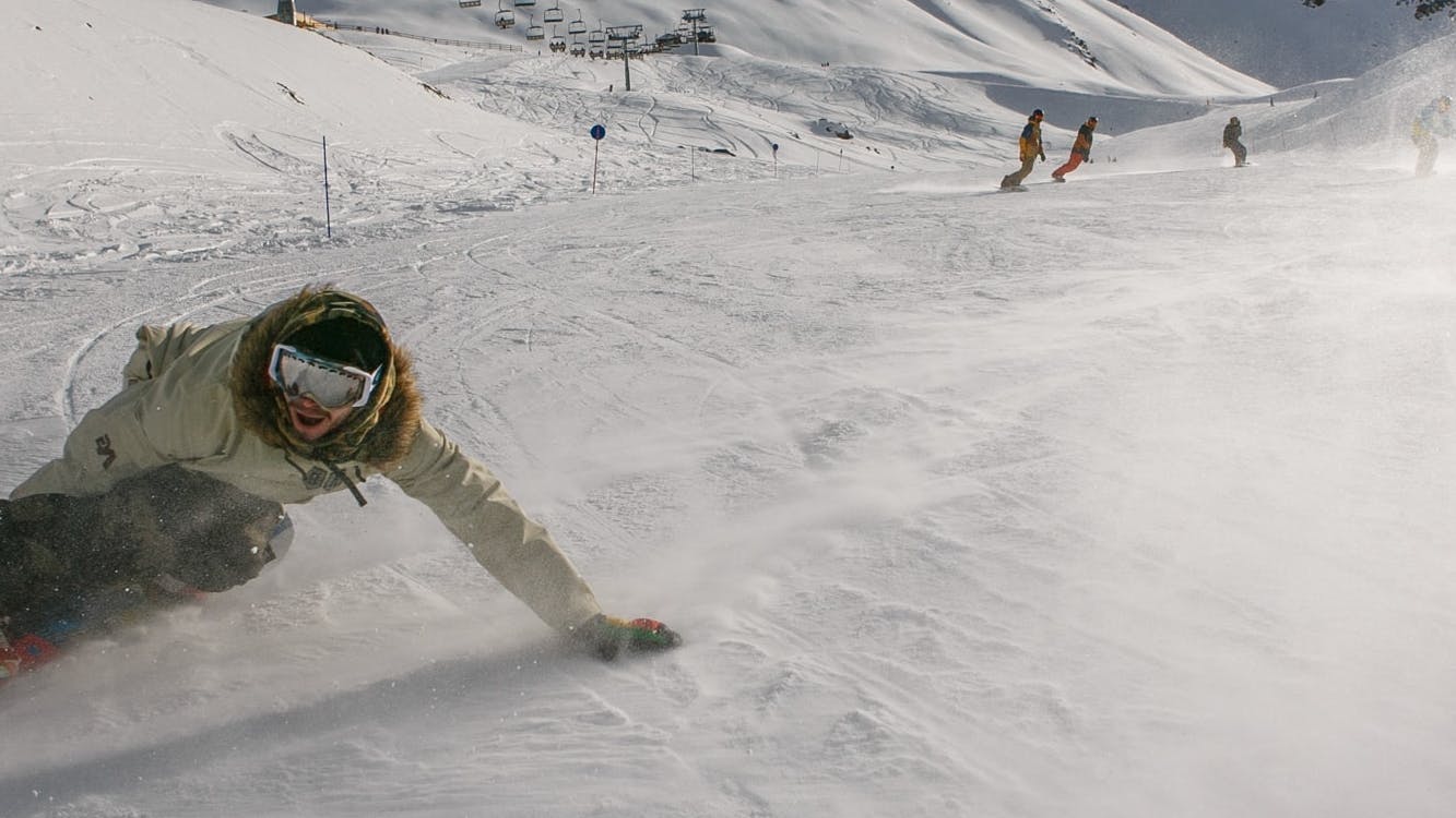A man carves down a ski run on his snowboard.