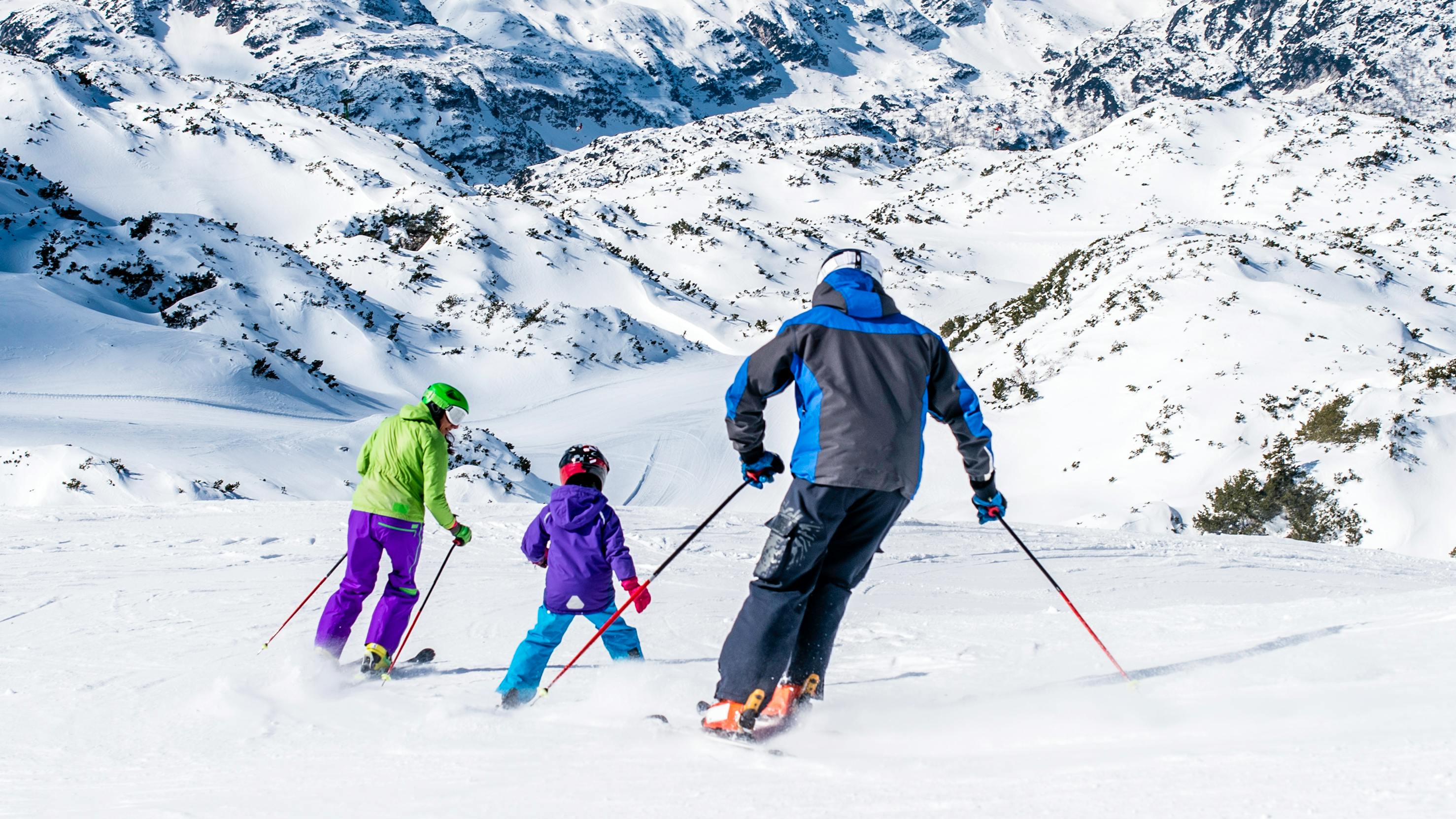 A man, woman, and child ski on a snowy hill