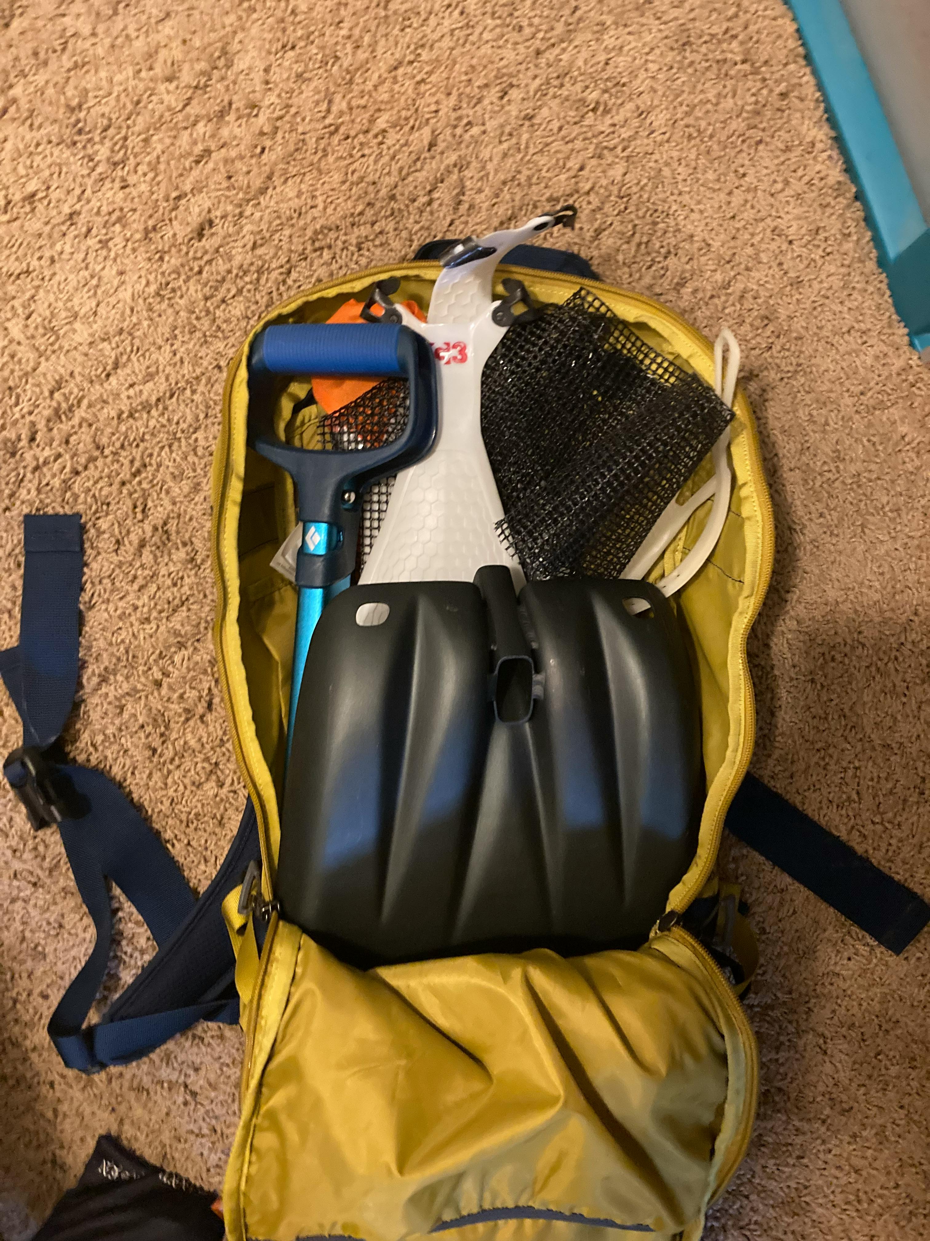 A shovel and some other tools in a Patagonia Snowdrifter 20L backpack.