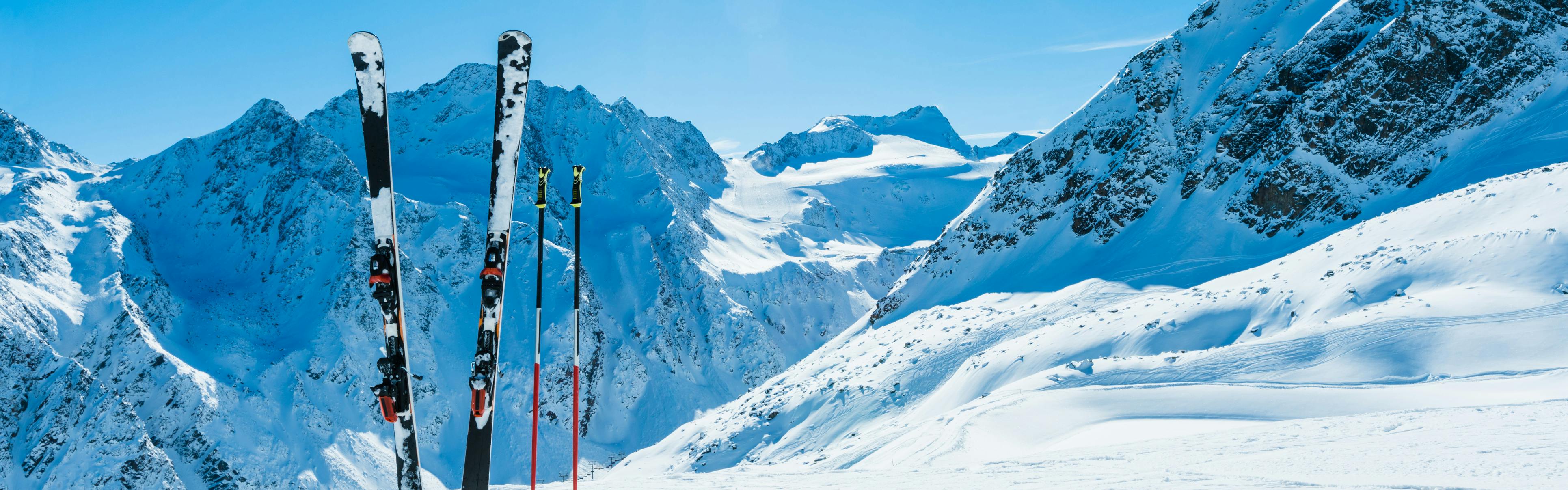 A pair of skis in the snow with mountains in the background