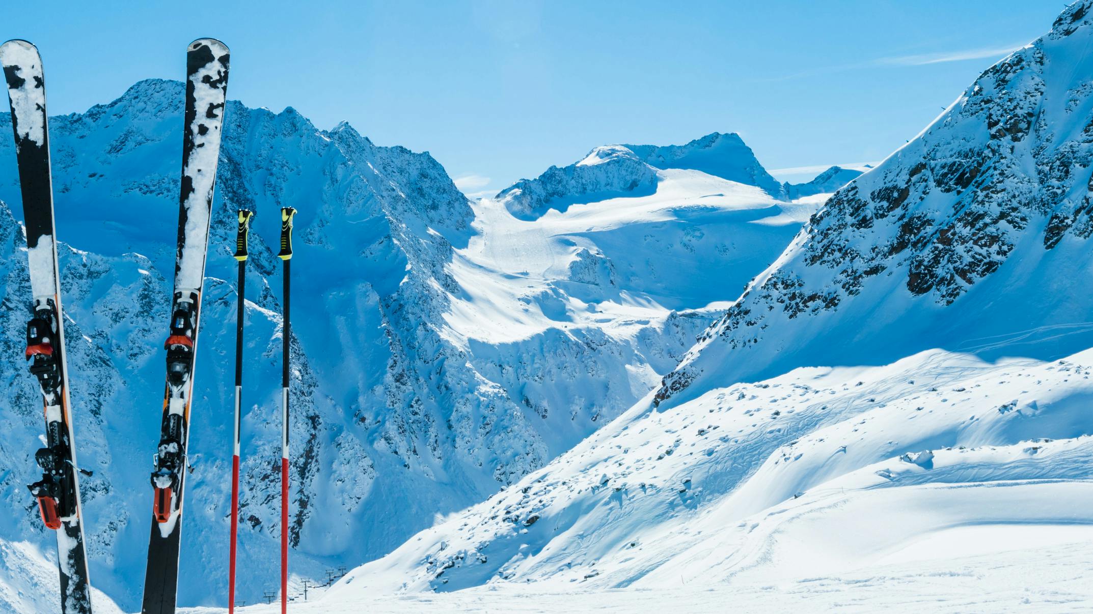 A pair of skis in the snow with mountains in the background