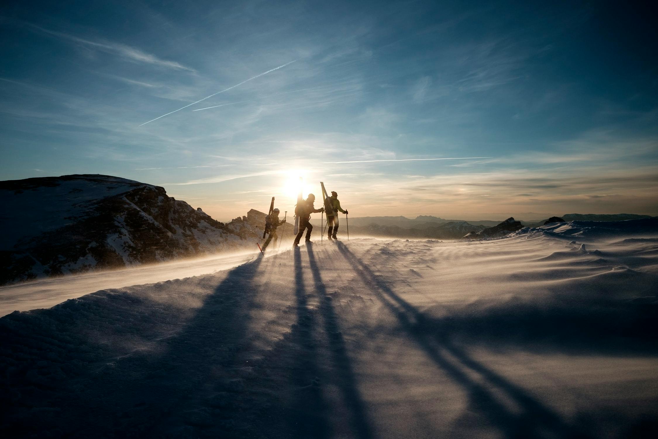 Three skiers hiking up a hill