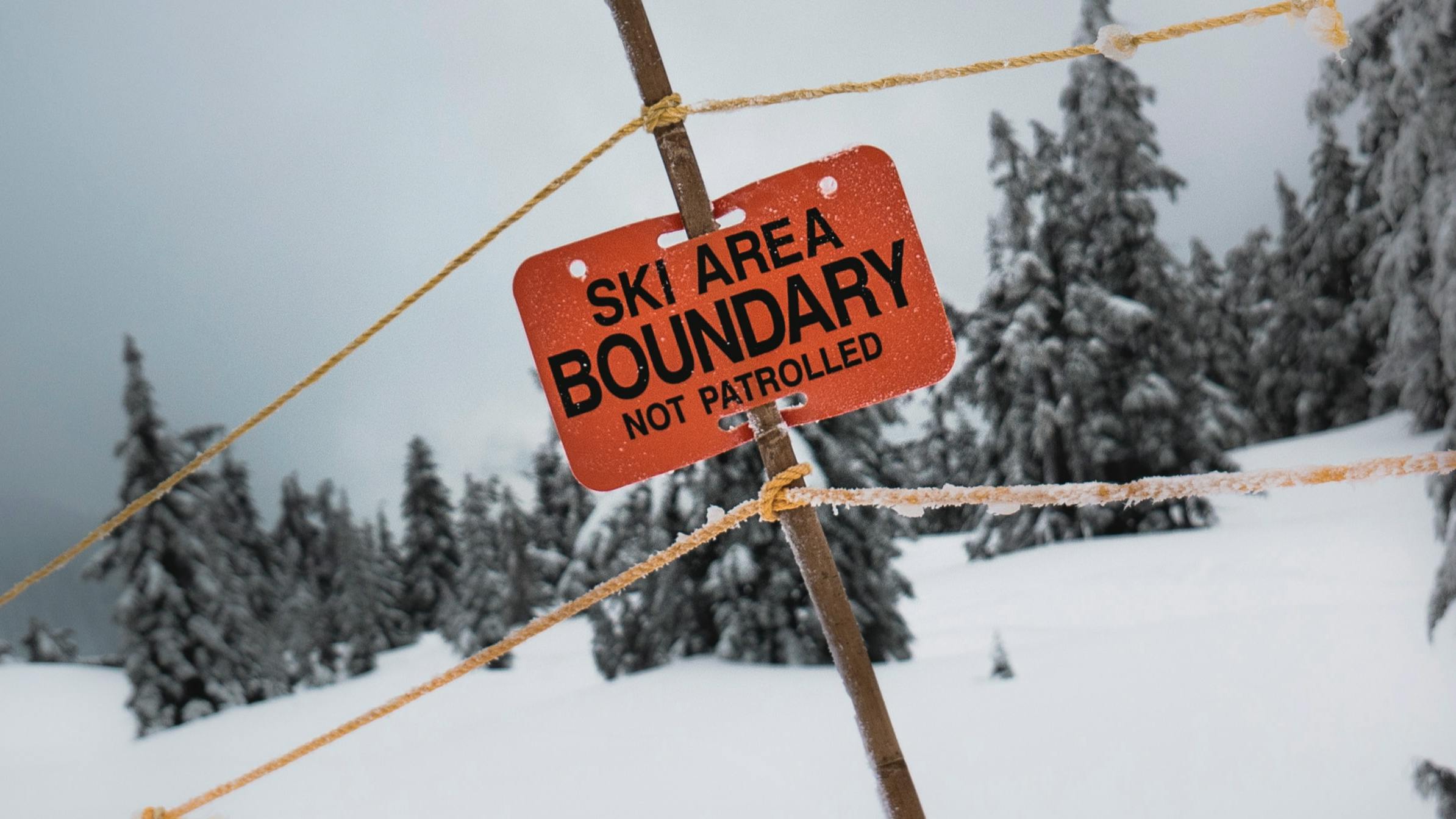 An orange sign reads "Ski Area Boundary. Not Patrolled." with signs roping off the boundary.