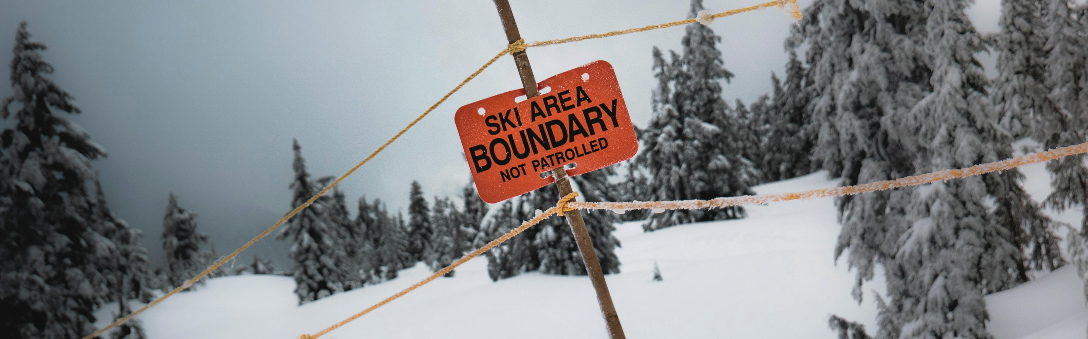An orange sign reads "Ski Area Boundary. Not Patrolled." with signs roping off the boundary.