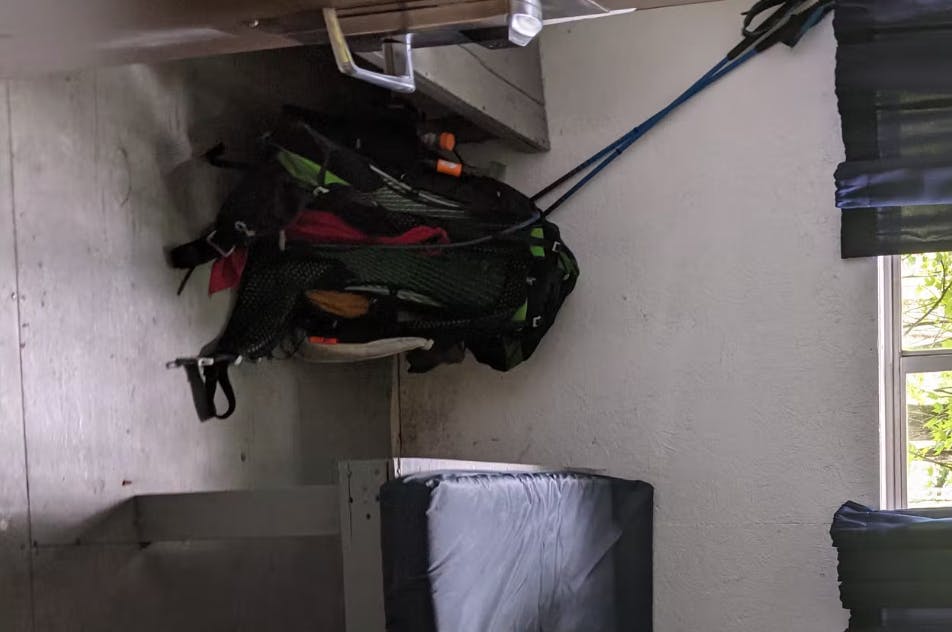 A backpack sits in a corner at a hostel.