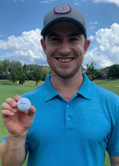 A man smiling holding a Srixon Z XV Star 7 Pure White Golf Ball on a golf course. 