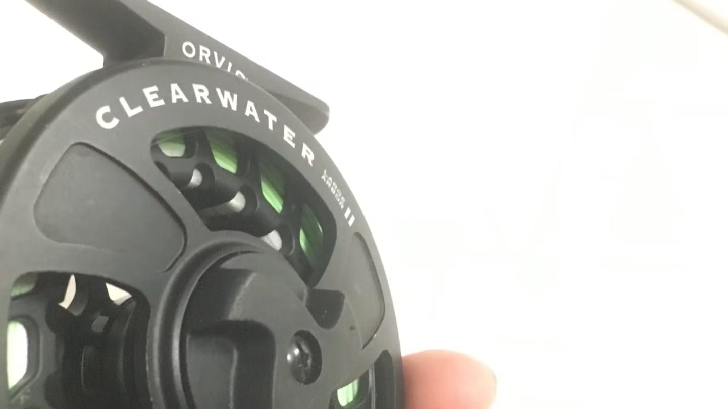 A hand holding the Orvis Clearwater LA Reel.