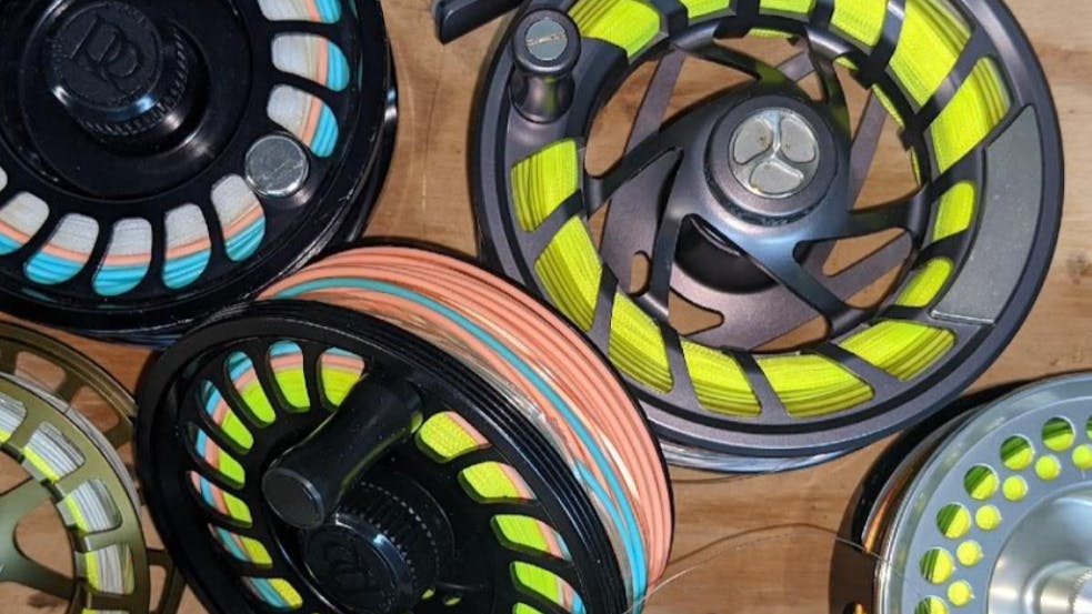 Several fly fishing reels lay in a pile. 