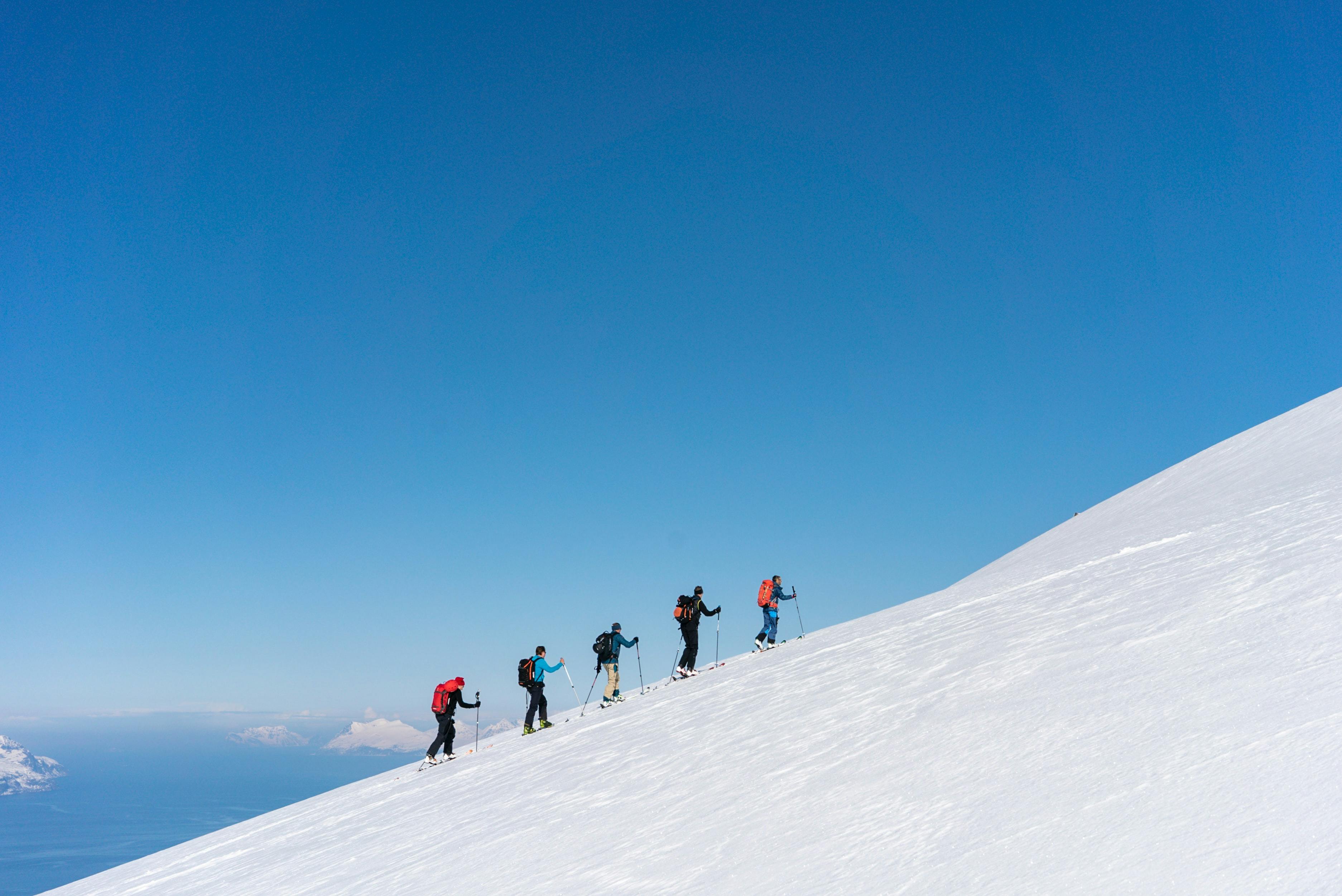 Skiers hike up a mountain.