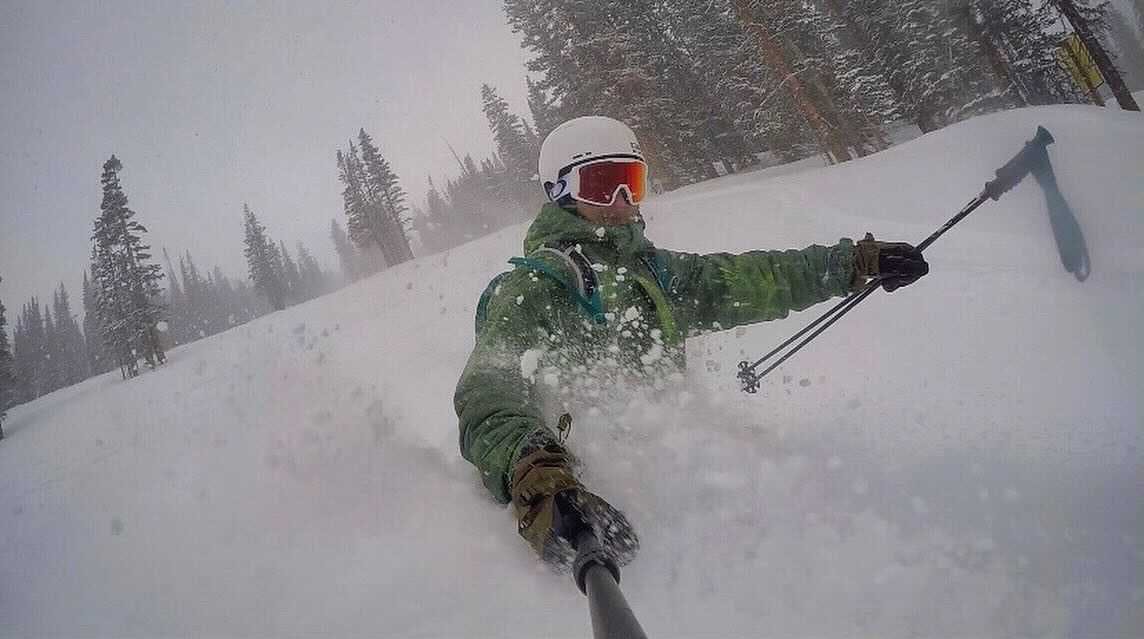 A skier heading down the slope and taking the photo with his selfie stick