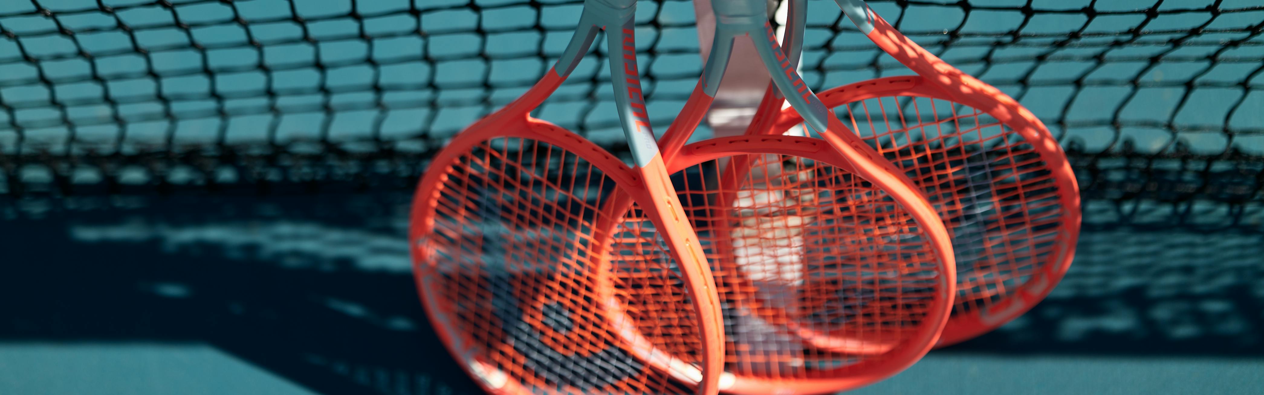 Three Head Radical racquets lean against a net.