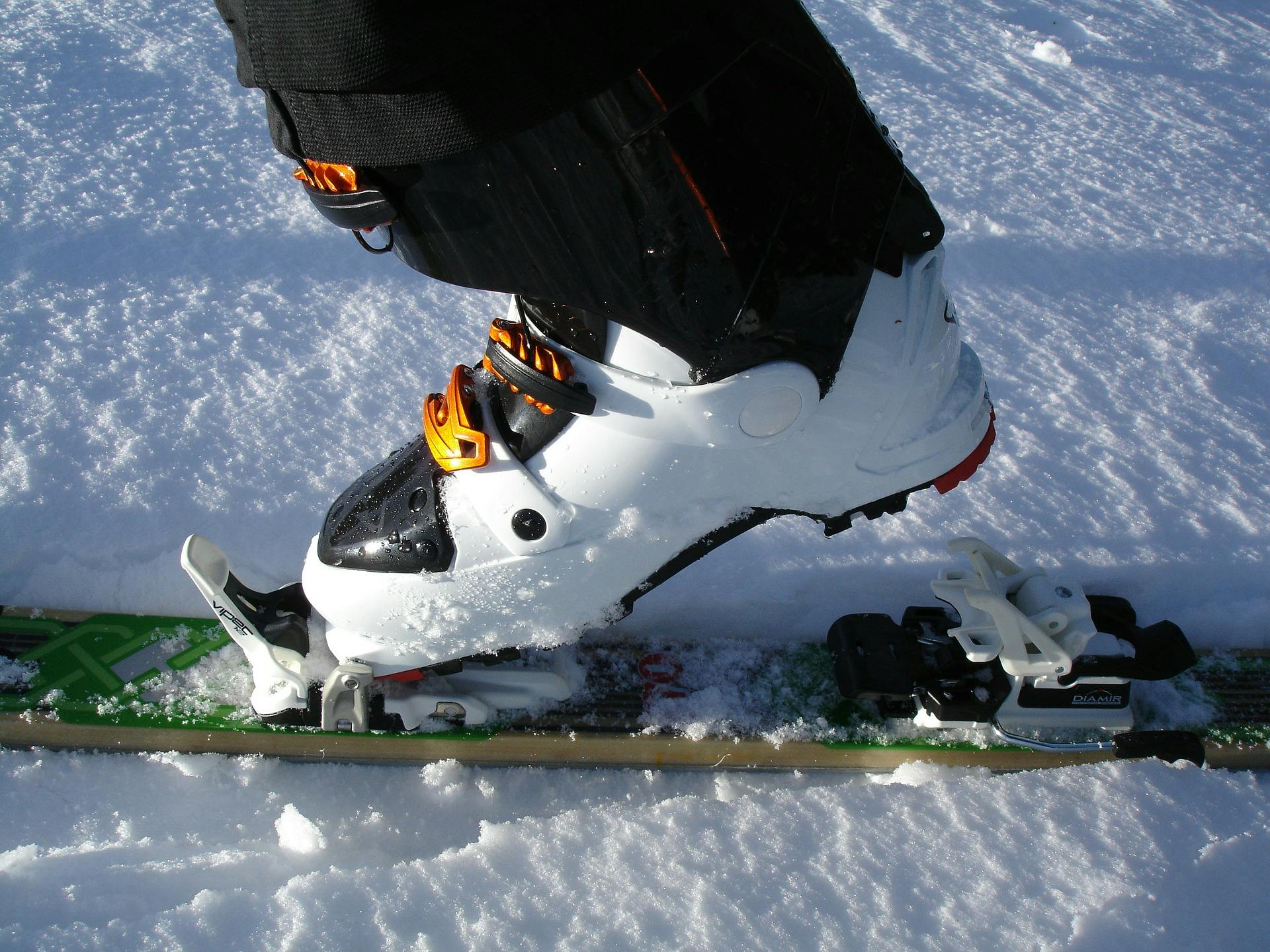 Someone stands with a ski in the snow and has their tech binding in tour mode.
