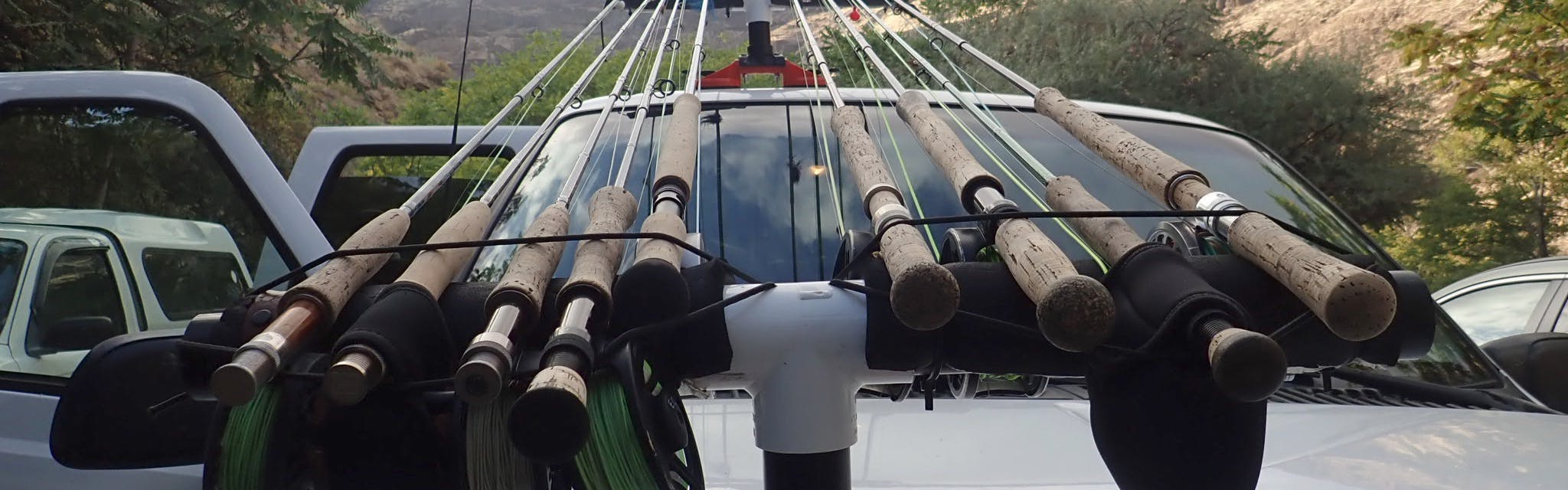 Nine fly fishing rods on a rack on the hood of a truck