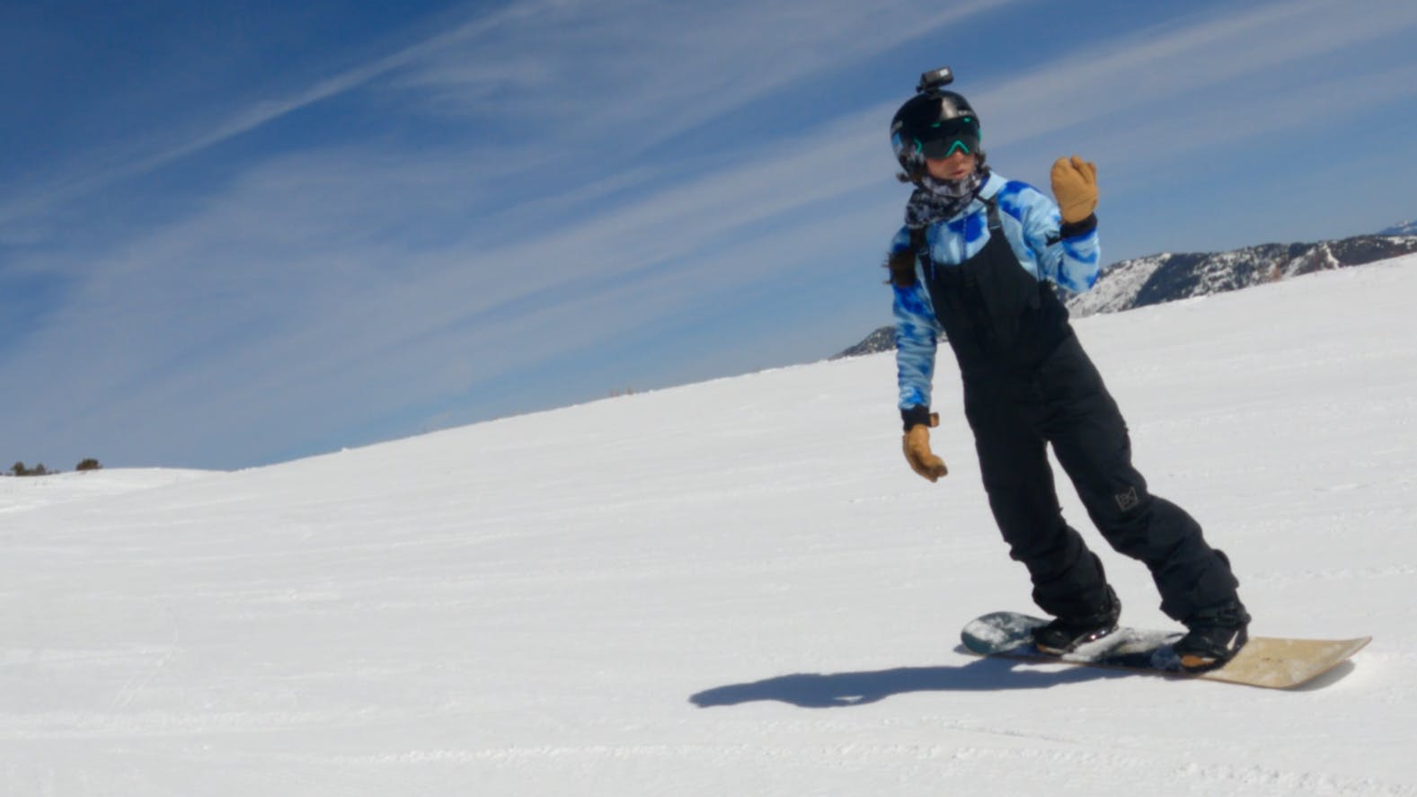 A snowboarder turning on the Arbor Cadence Camber Snowboard. 