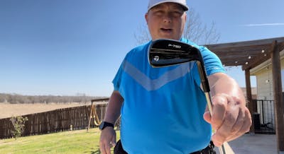 A man holds the TaylorMade P790 Black Iron.