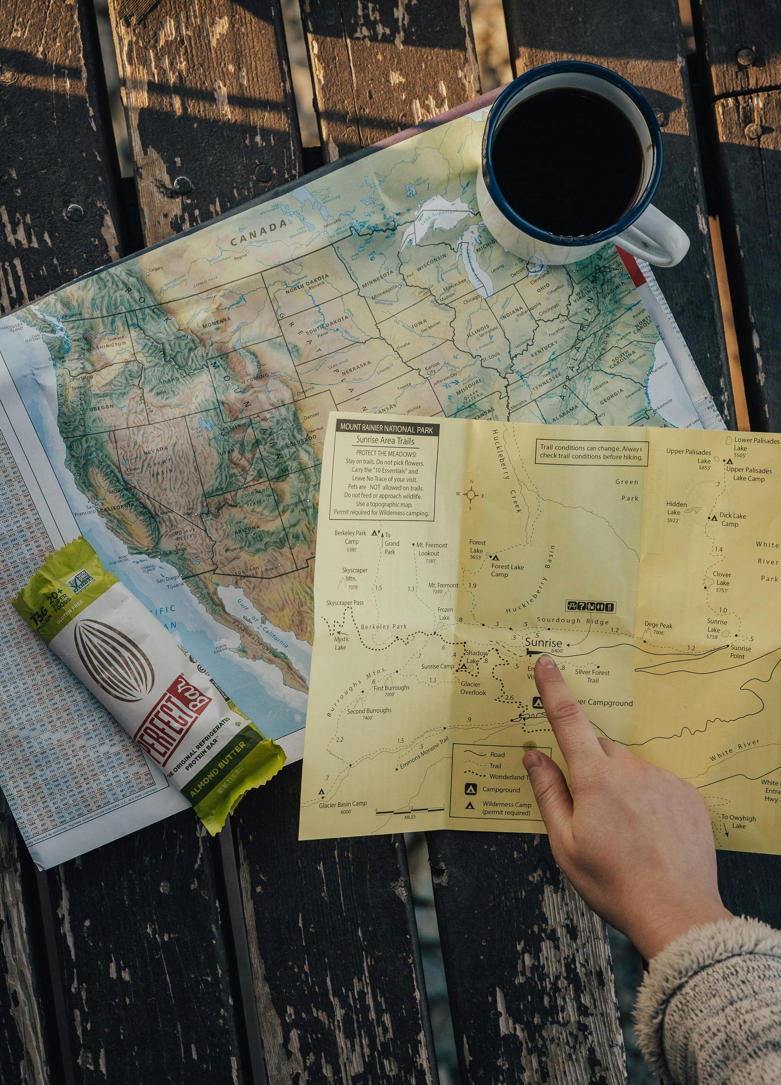 A hand pointing at a map with a protein bar sitting on the map. 