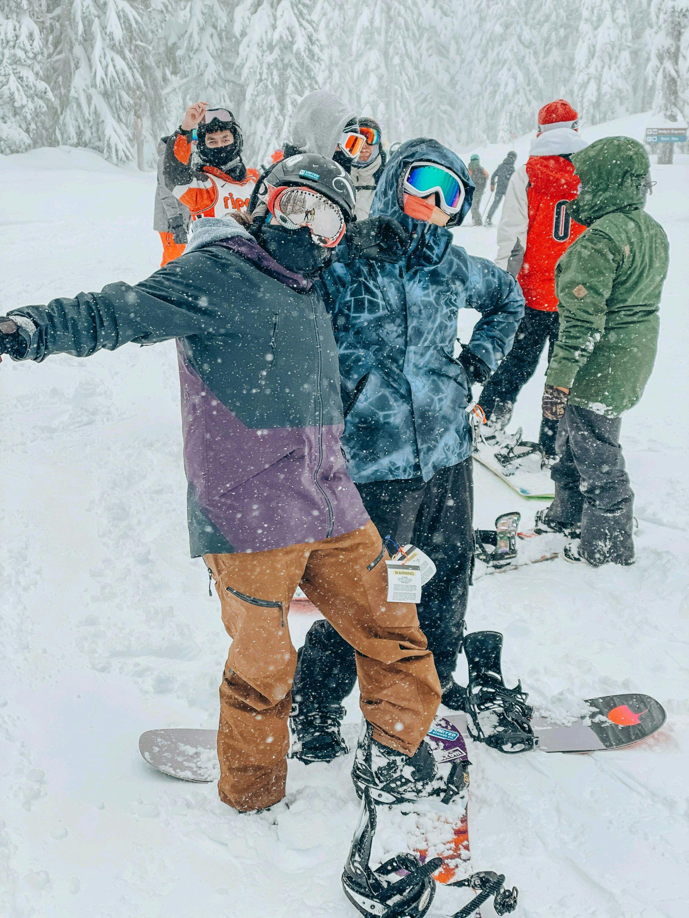 Several snowboarders in the snow, one wearing the Mountain Hardwear Men's Boundary Ridge™ GORE-TEX® Bib Pants.