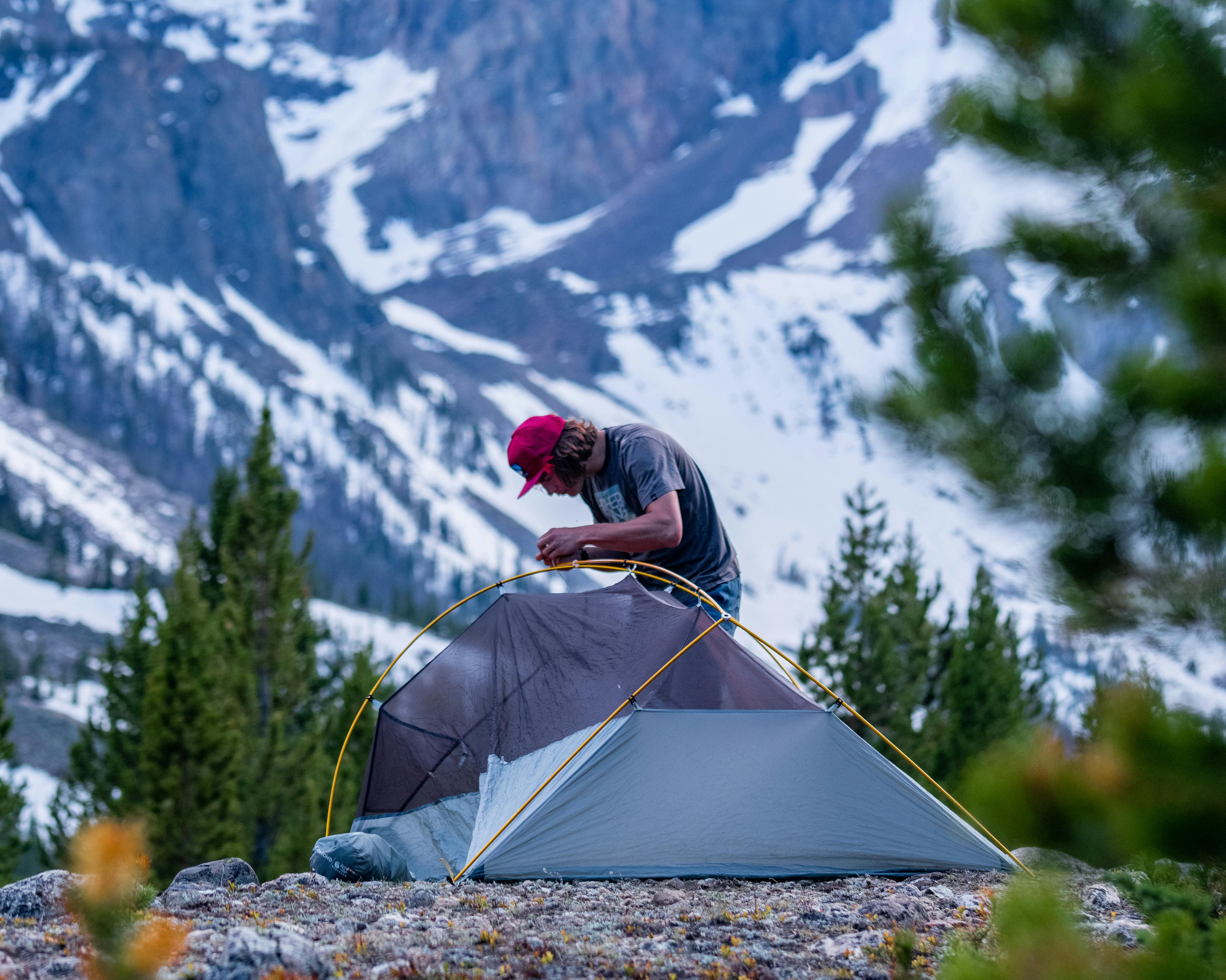 Curated expert Kael Van Buskirk building his tent with dramatic mountain scenery in the background