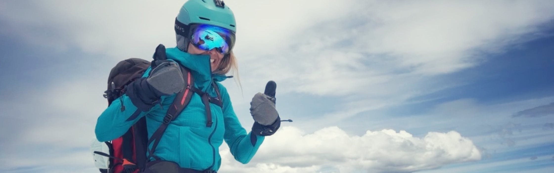 A woman wearing snowboard gear giving two thumbs up in her Dakine Sequoia GORE-TEX gloves. She is wearing a helmet and goggles. 