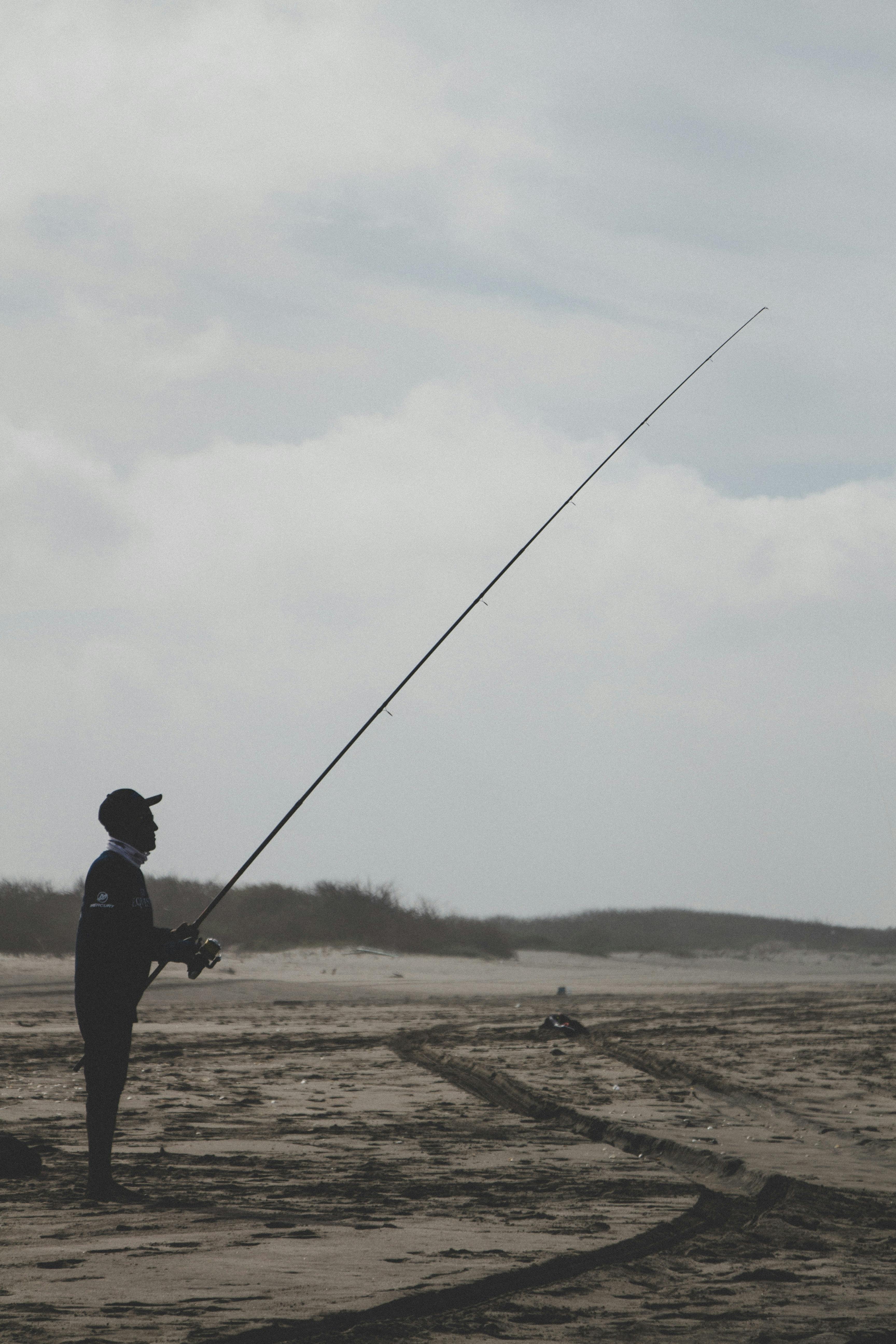 A fisherman standing on a beach. 