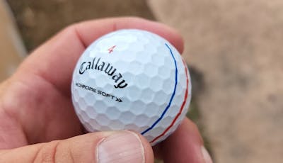 A hand holding a Callaway 2022 Chrome Soft Triple Track Golf Ball.