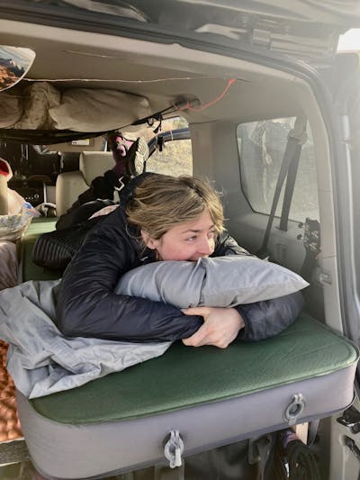 A person sleeps in the back of a car on the Exped sleeping mat. 