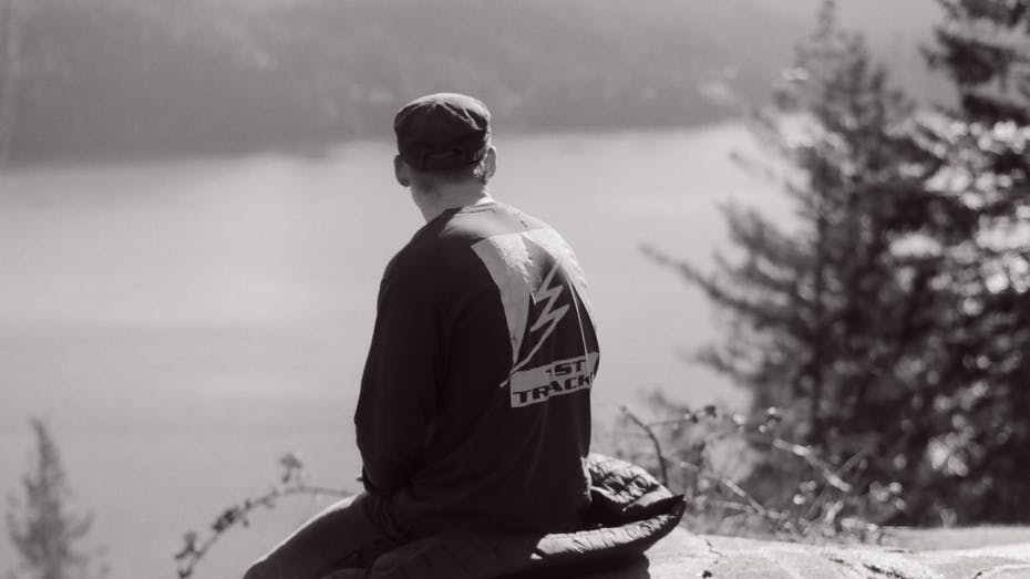 A man looks out at a lake at Quarry Rock with his back to the camera