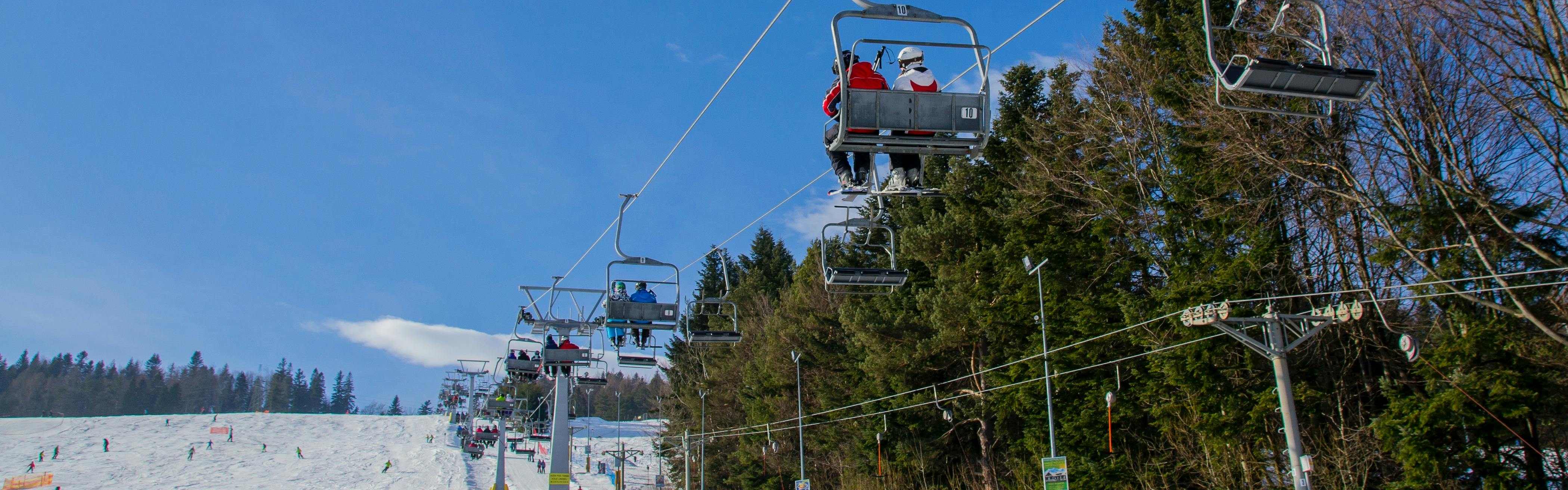 People ride a chairlift up a snowy mountain