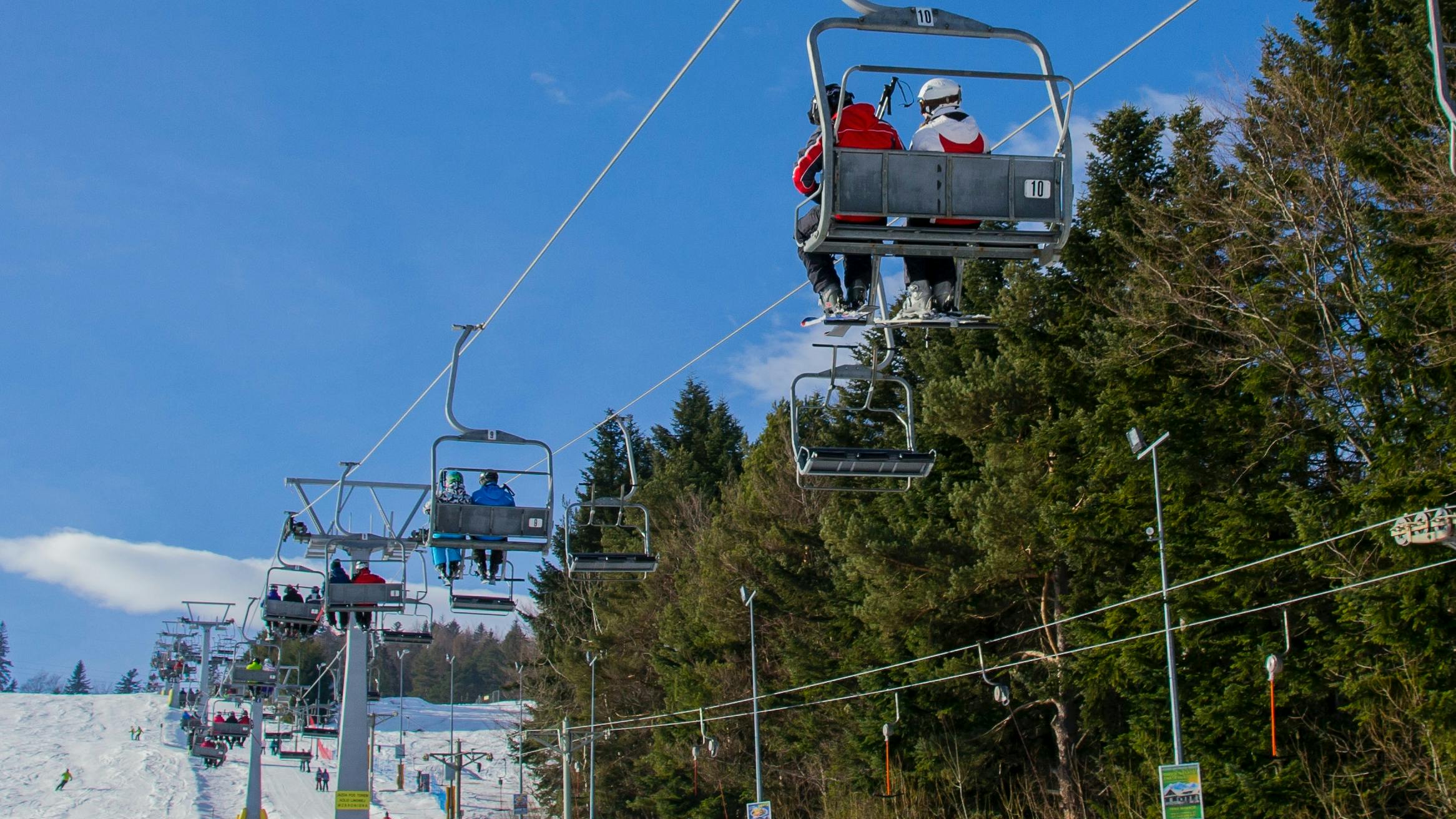 People ride a chairlift up a snowy mountain