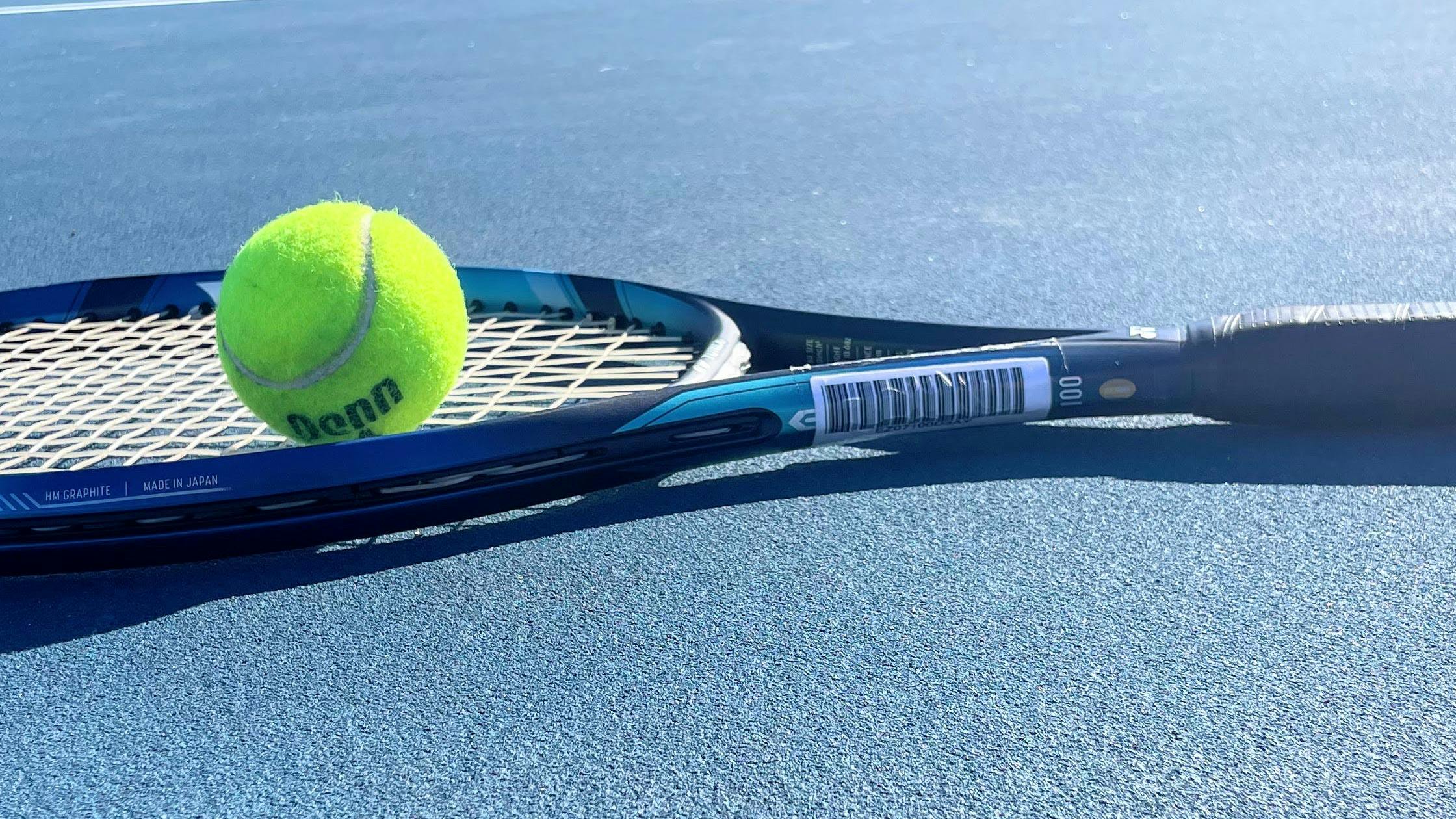 The Yonex EZone 100 Racquet with a tennis ball on it. 