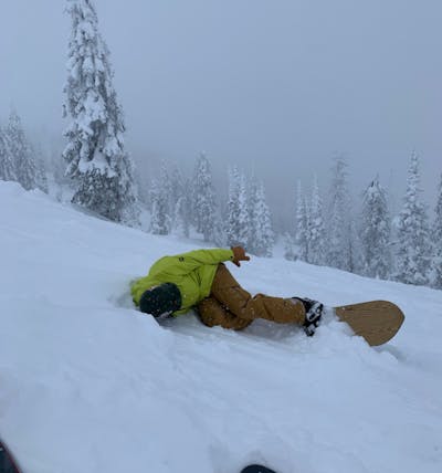 A snowboarder laying in the snow. 