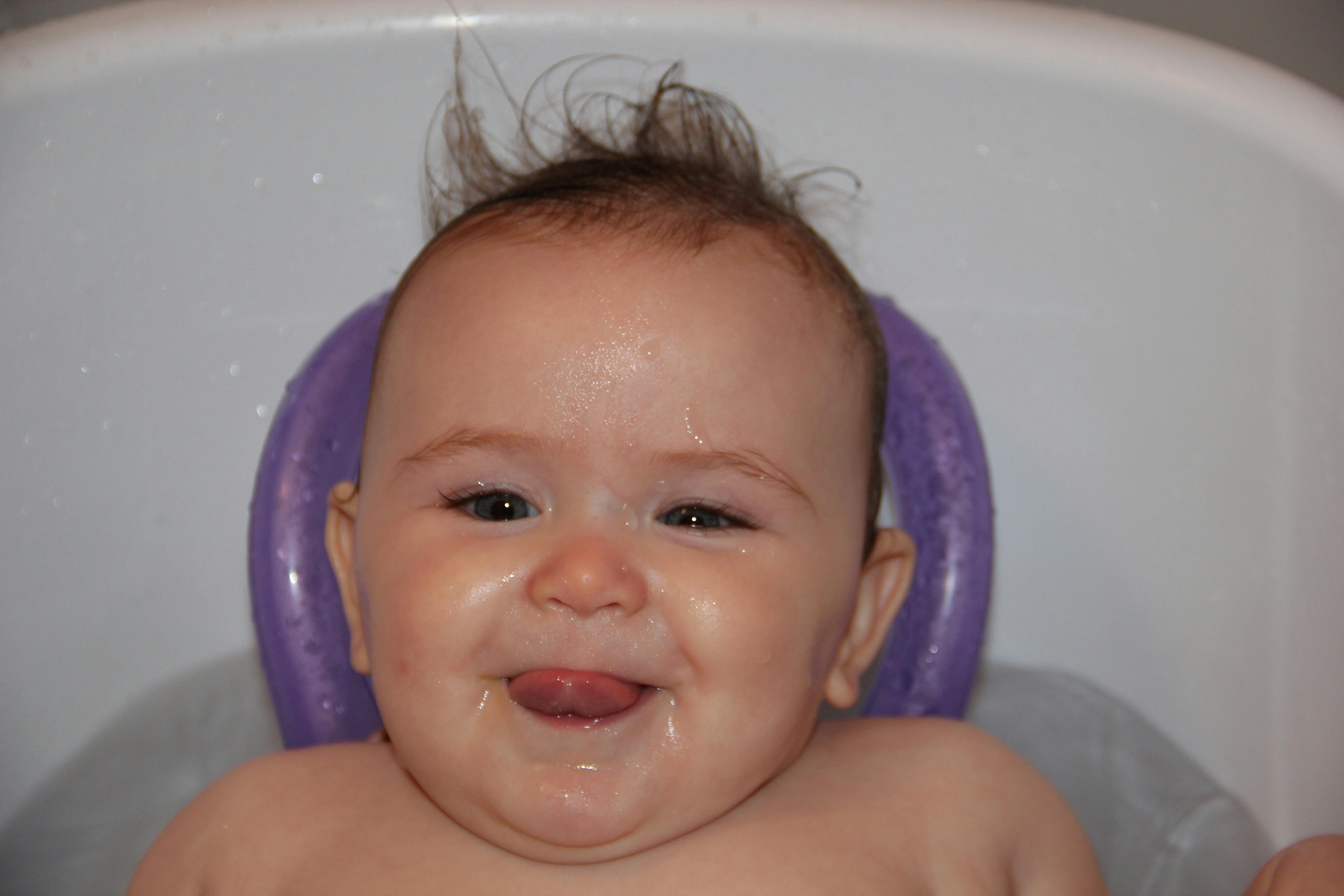 A baby sits in a bathtub. 
