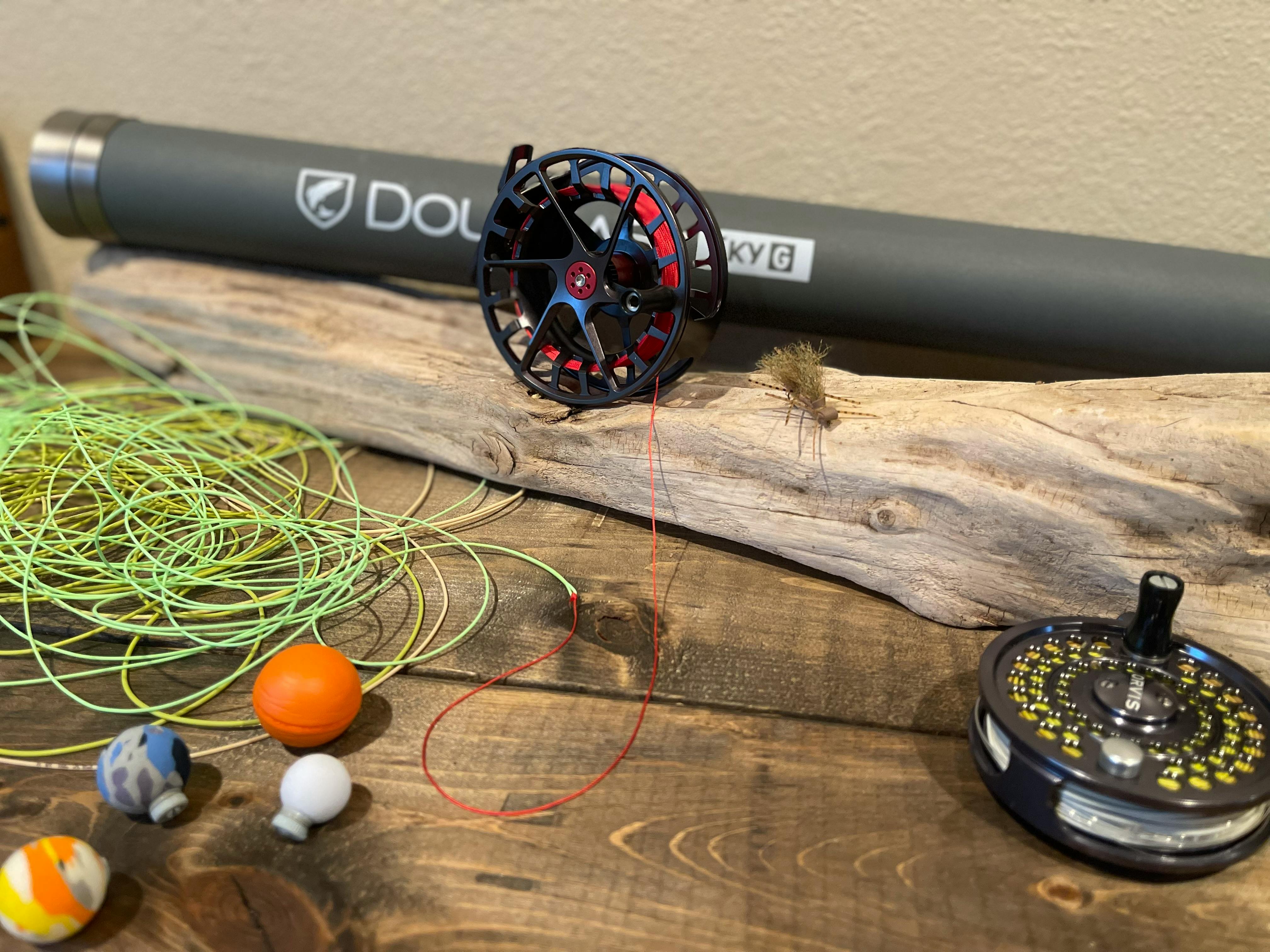 A fly reel is unwound with yellow line and red backing coming off of it. 