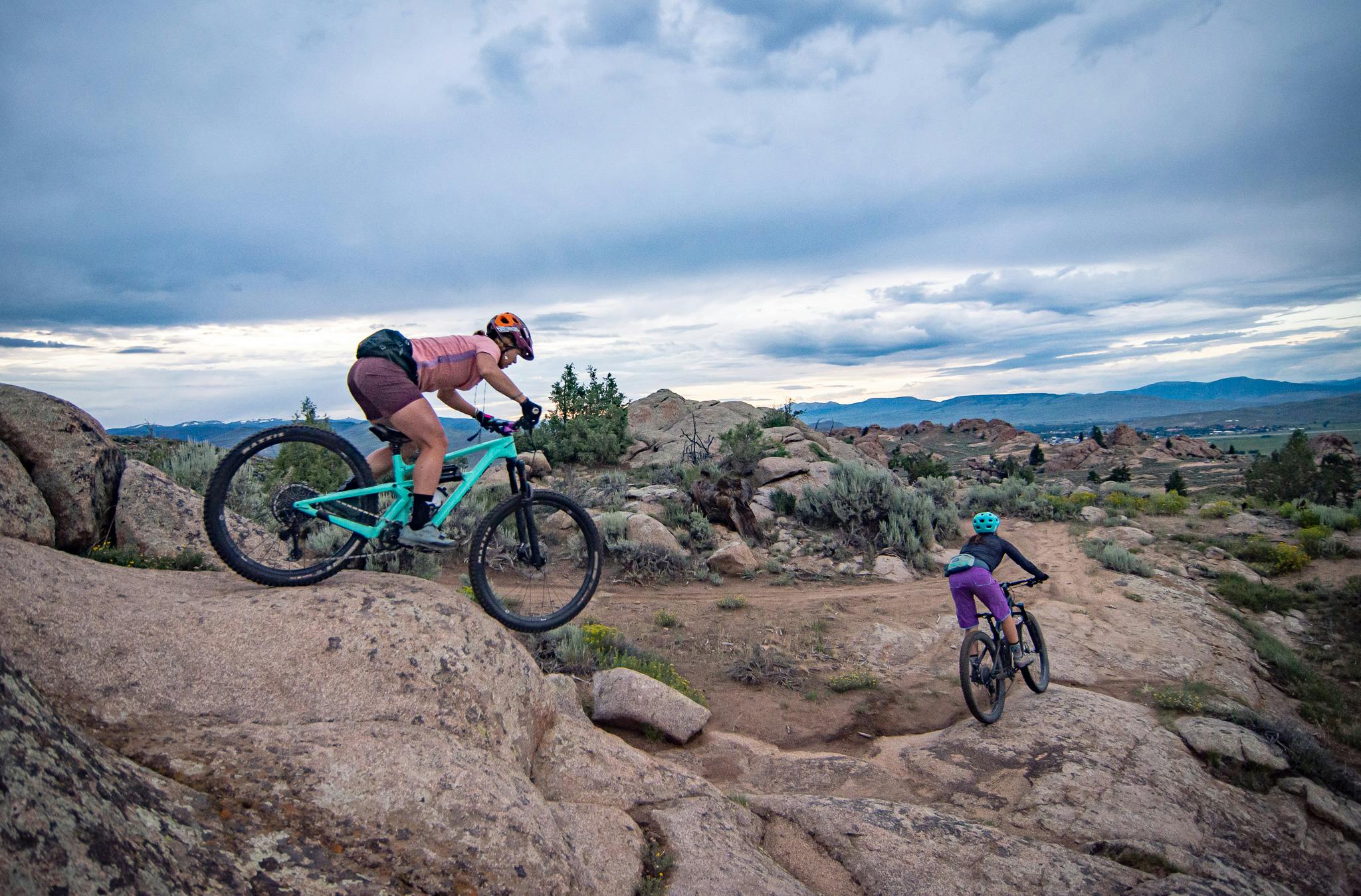 Two women on mountain bikes adventuring through a rocky desert landscape.
