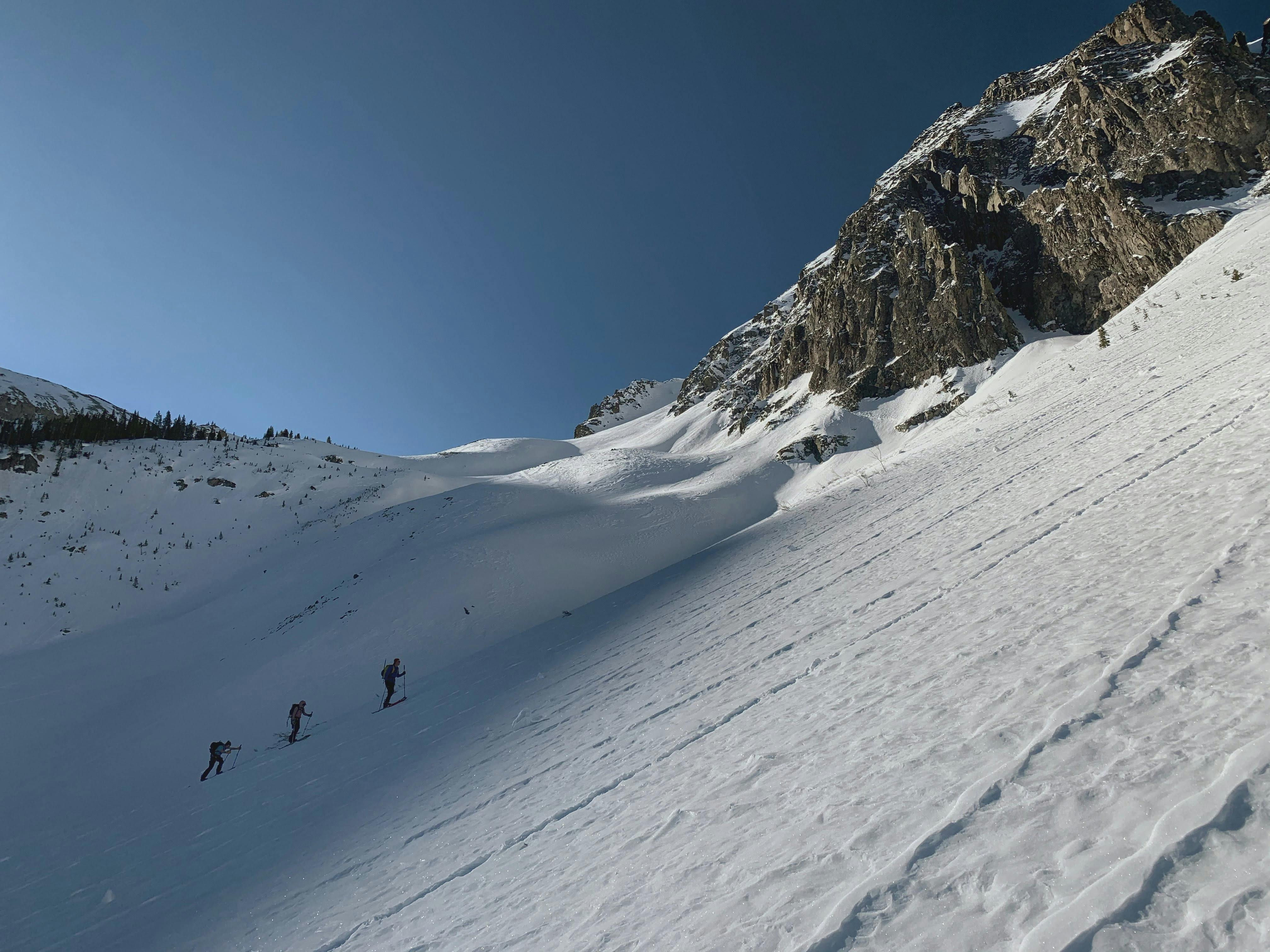 Three skiers walking up a mountain. 
